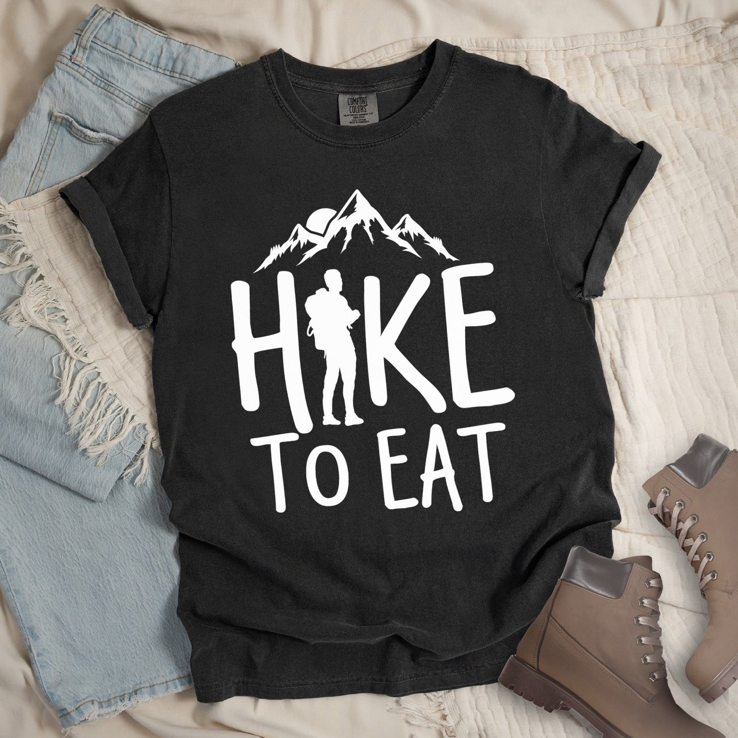 Dark grey shirt with a Hiking design featuring mountain silhouette and shows 'Hike To Eat' phrase in bold text