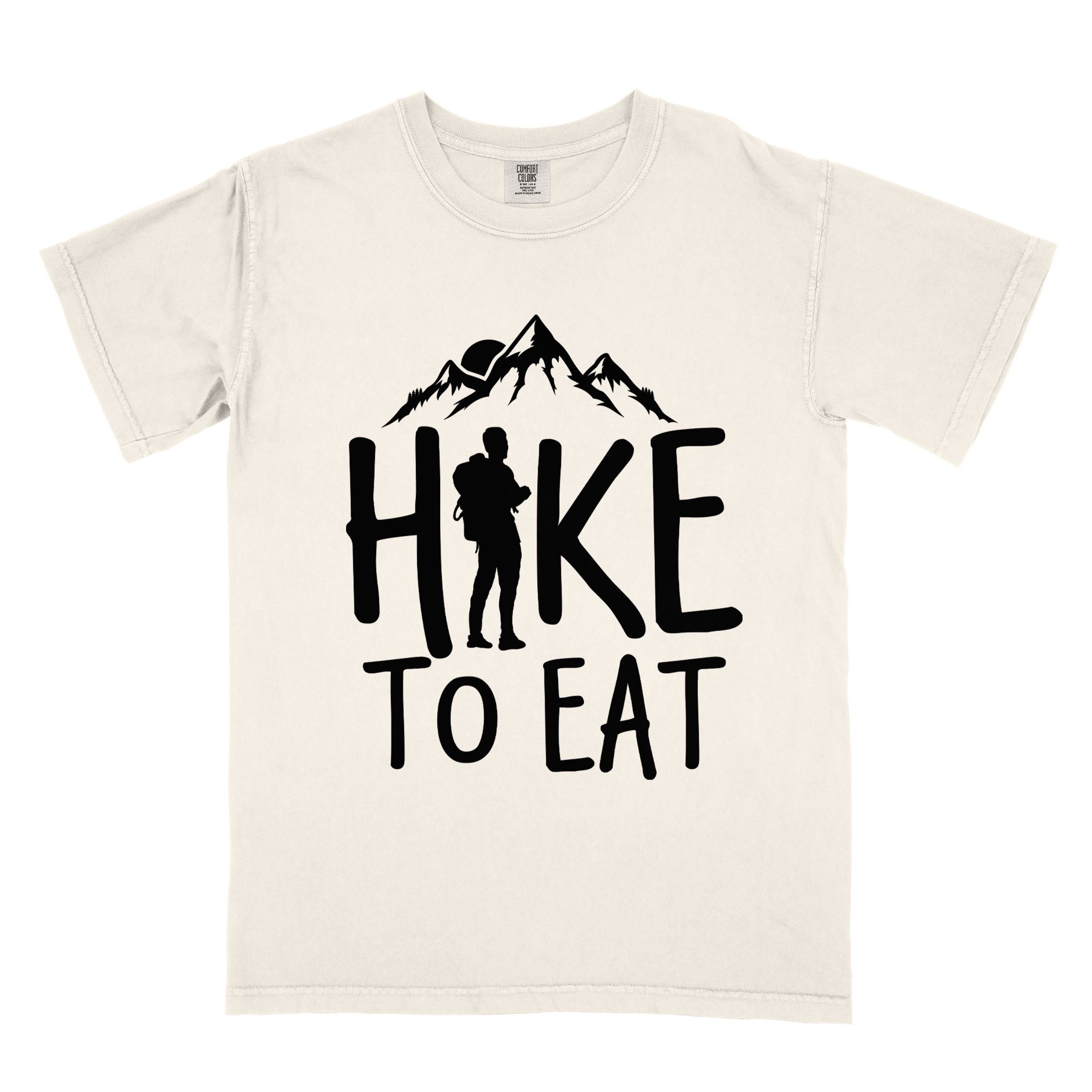 Ivory "Hike to Eat" colored statement tee with bold typography, mountains, birds, sunrise, perfect for food motivated individuals.