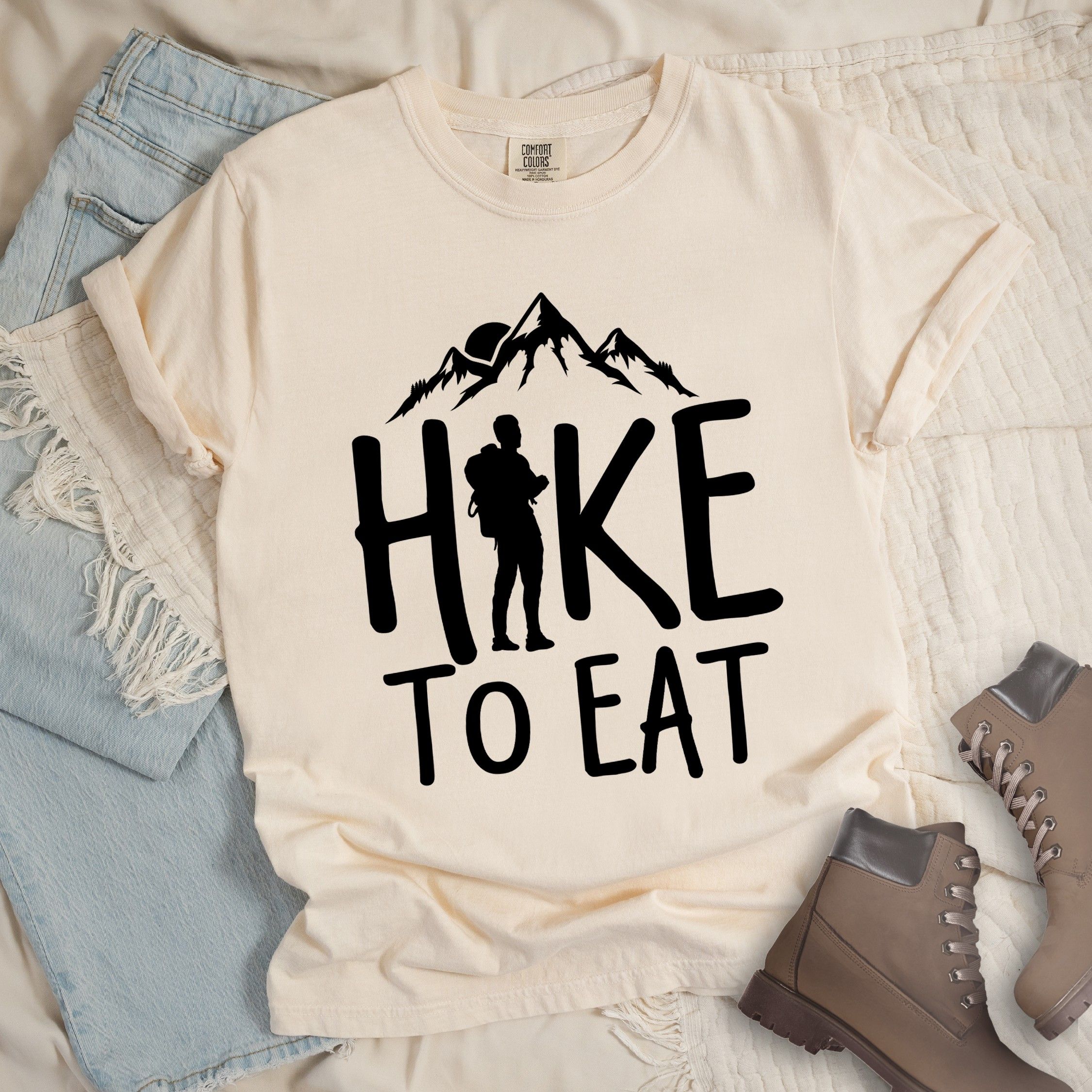 Ivory shirt with a Hiking design featuring mountain silhouette and shows 'Hike To Eat' phrase in bold text