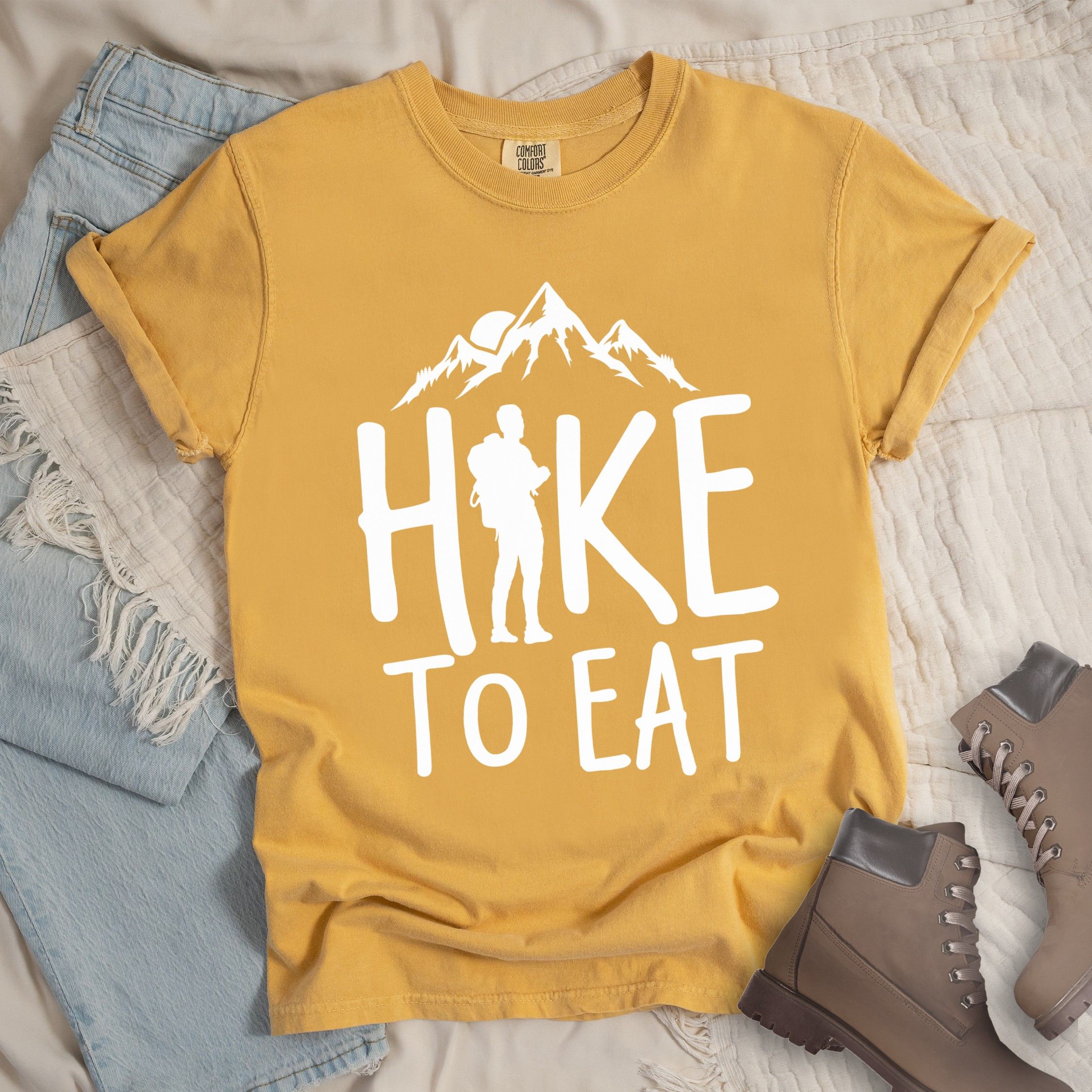 Yellow shirt with a Hiking design featuring mountain silhouette and shows 'Hike To Eat' phrase in bold text