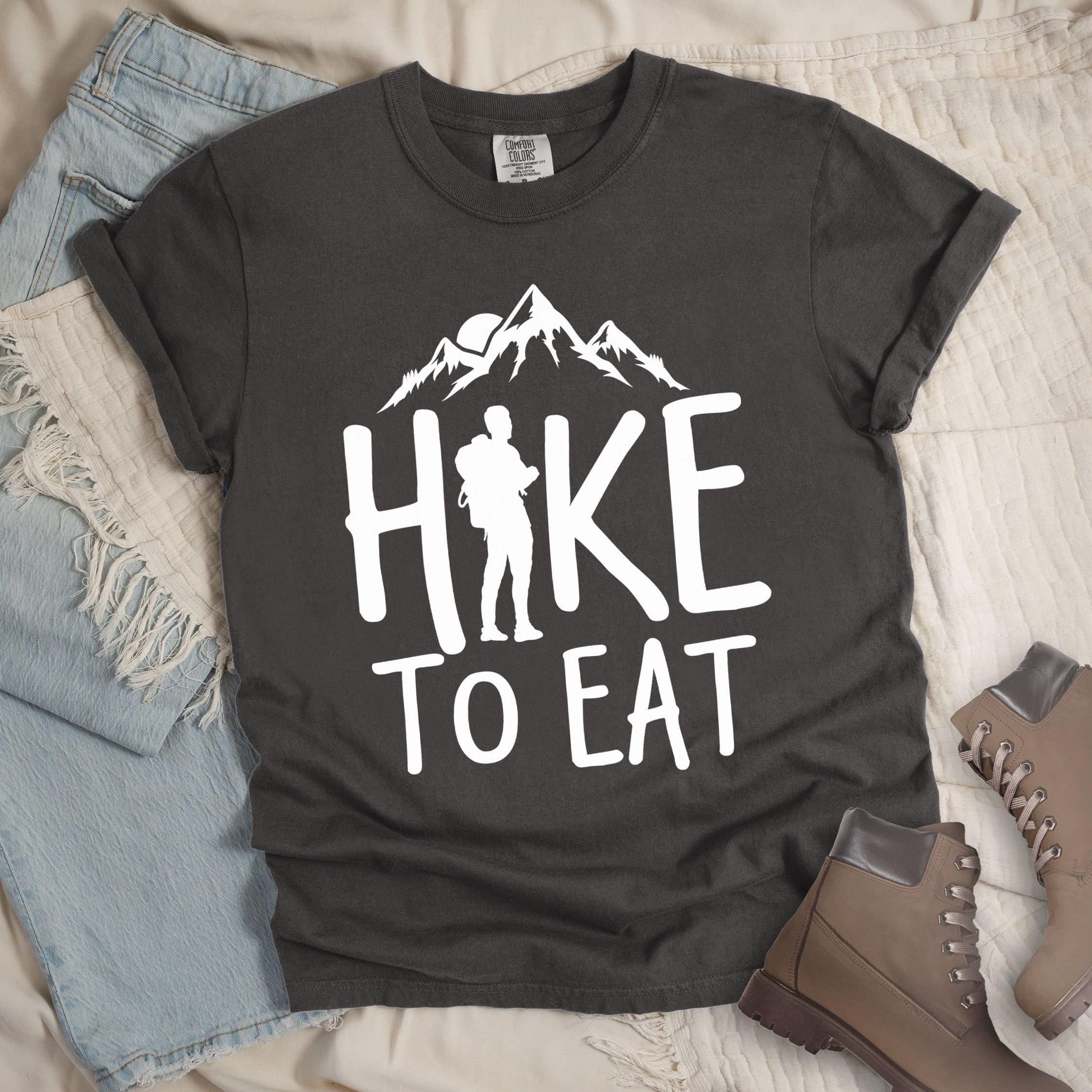 Dark grey shirt with a Hiking design featuring mountain silhouette and shows 'Hike To Eat' phrase in bold text