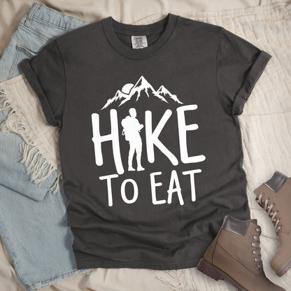 Dark grey shirt with a Hiking design featuring mountain silhouette and shows 'Hike To Eat' phrase in bold text