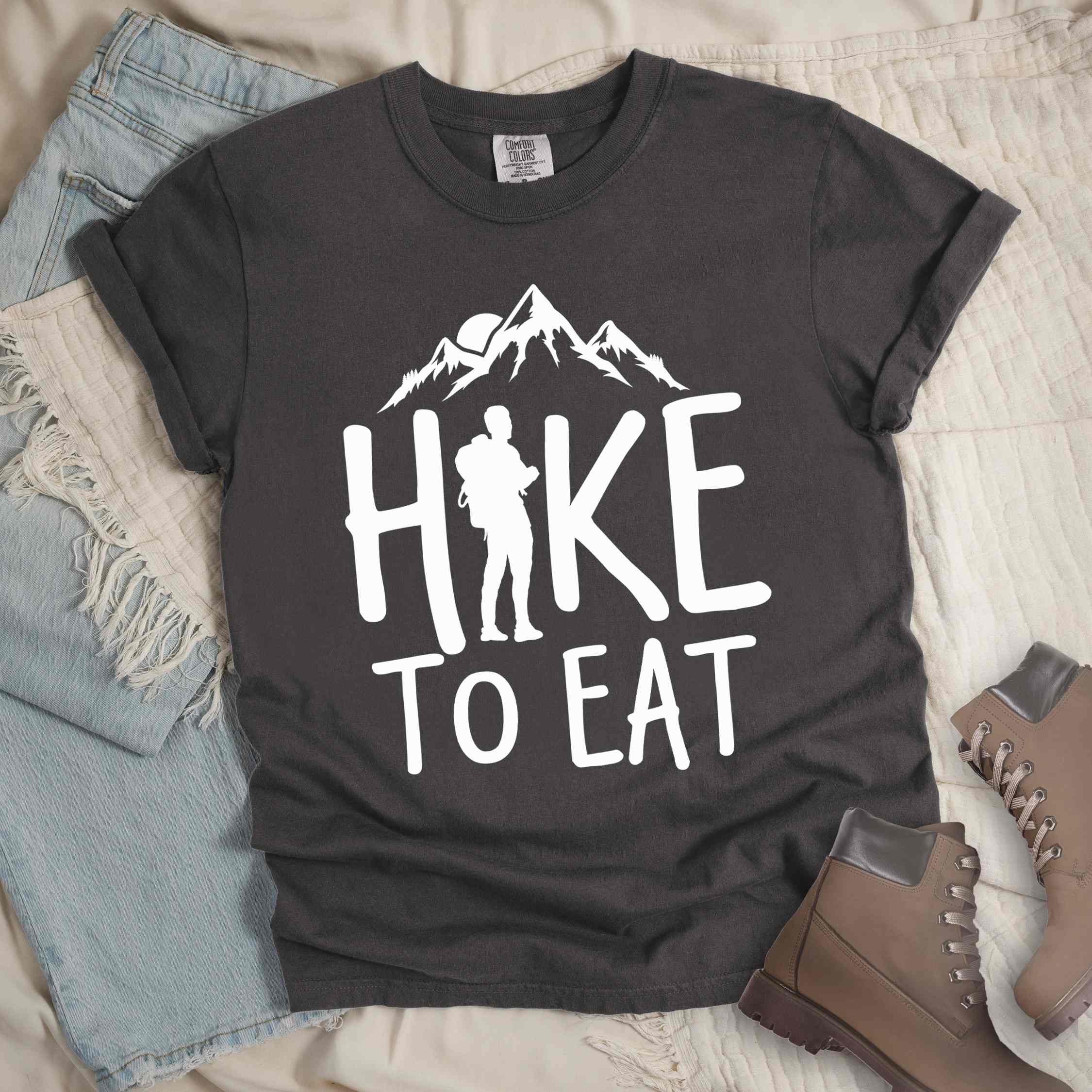 Pepper "Hike to Eat" colored statement tee with bold typography, mountains, birds, sunrise, perfect for food motivated individuals.