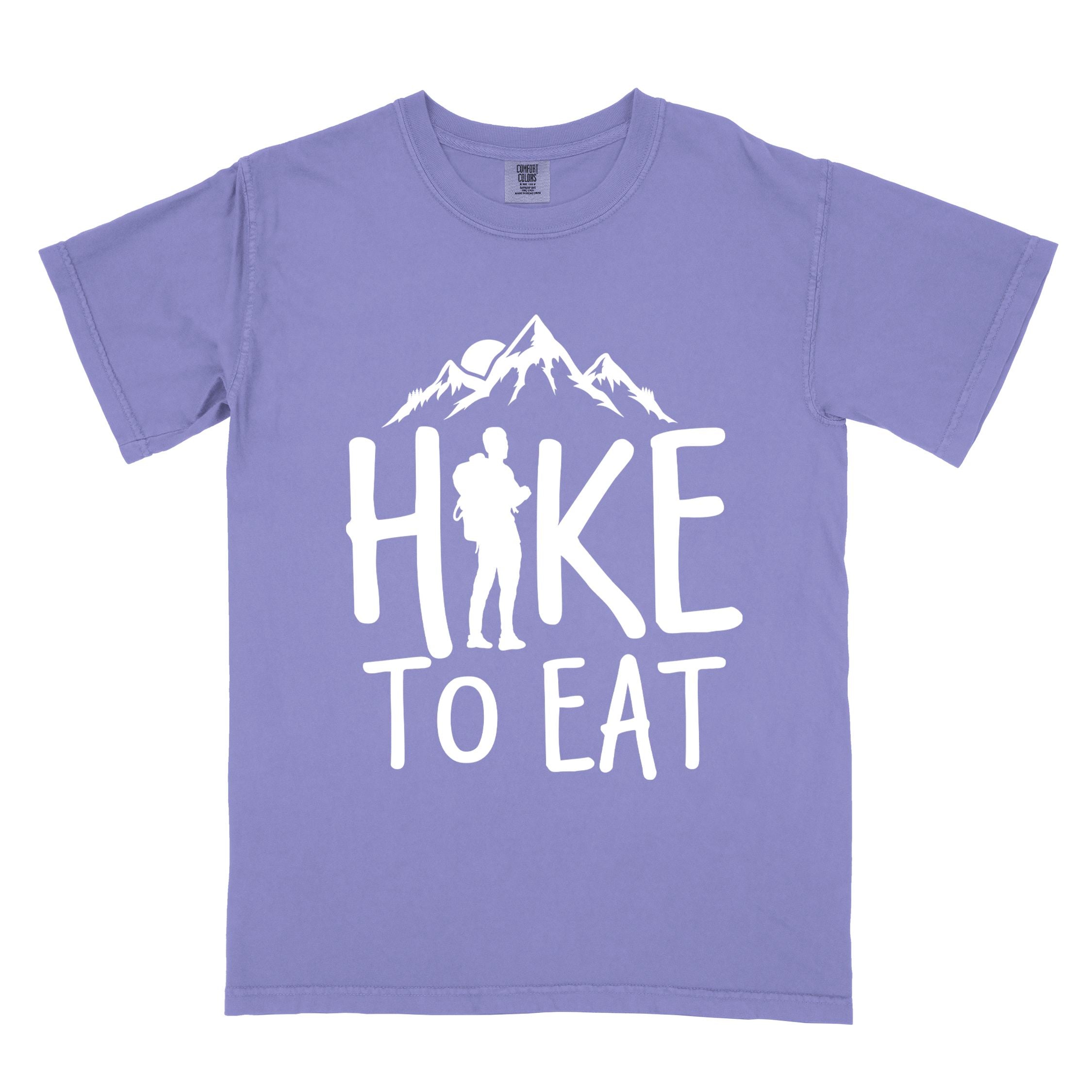 Violet "Hike to Eat" colored statement tee with bold typography, mountains, birds, sunrise, perfect for food motivated individuals.