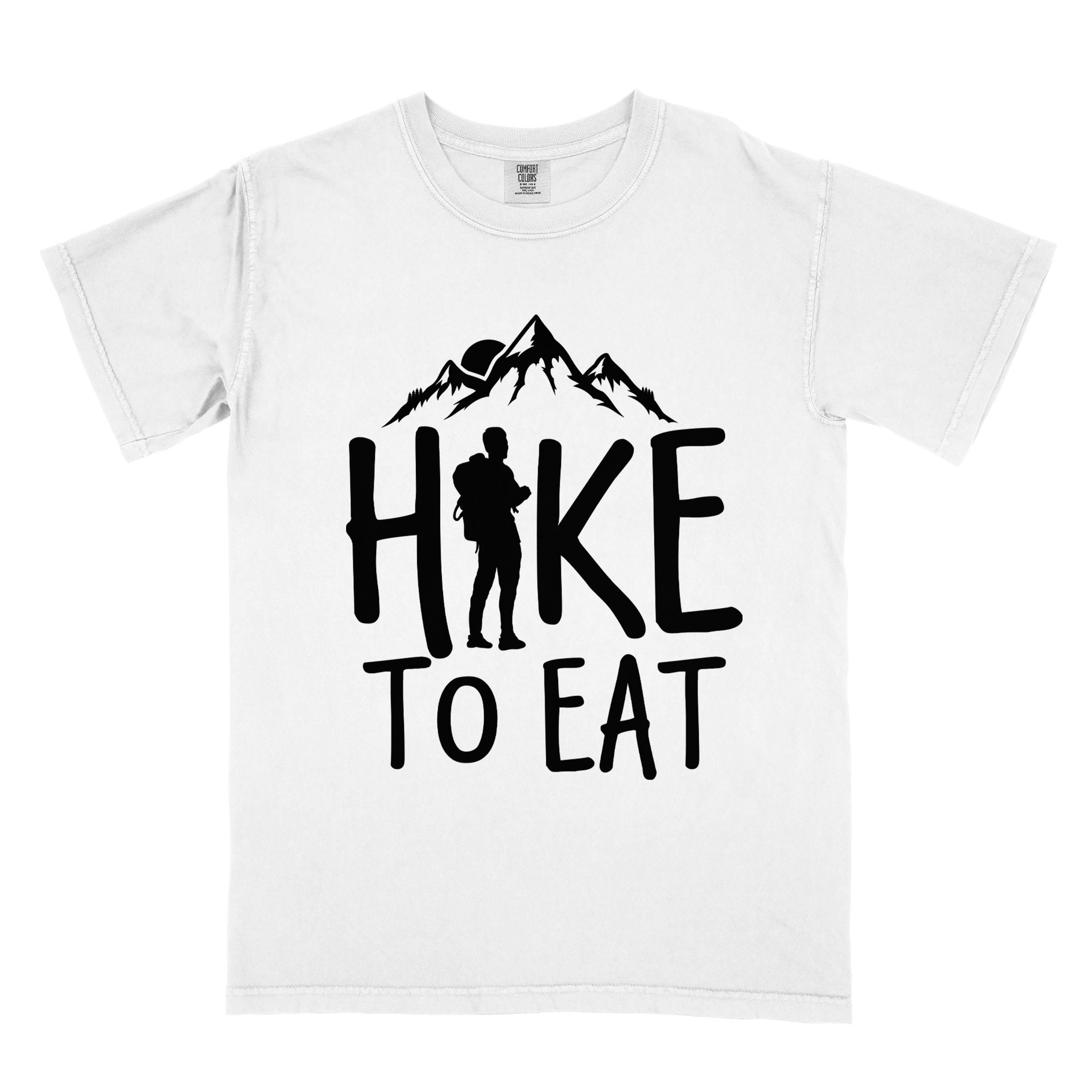 White "Hike to Eat" colored statement tee with bold typography, mountains, birds, sunrise, perfect for food motivated individuals.