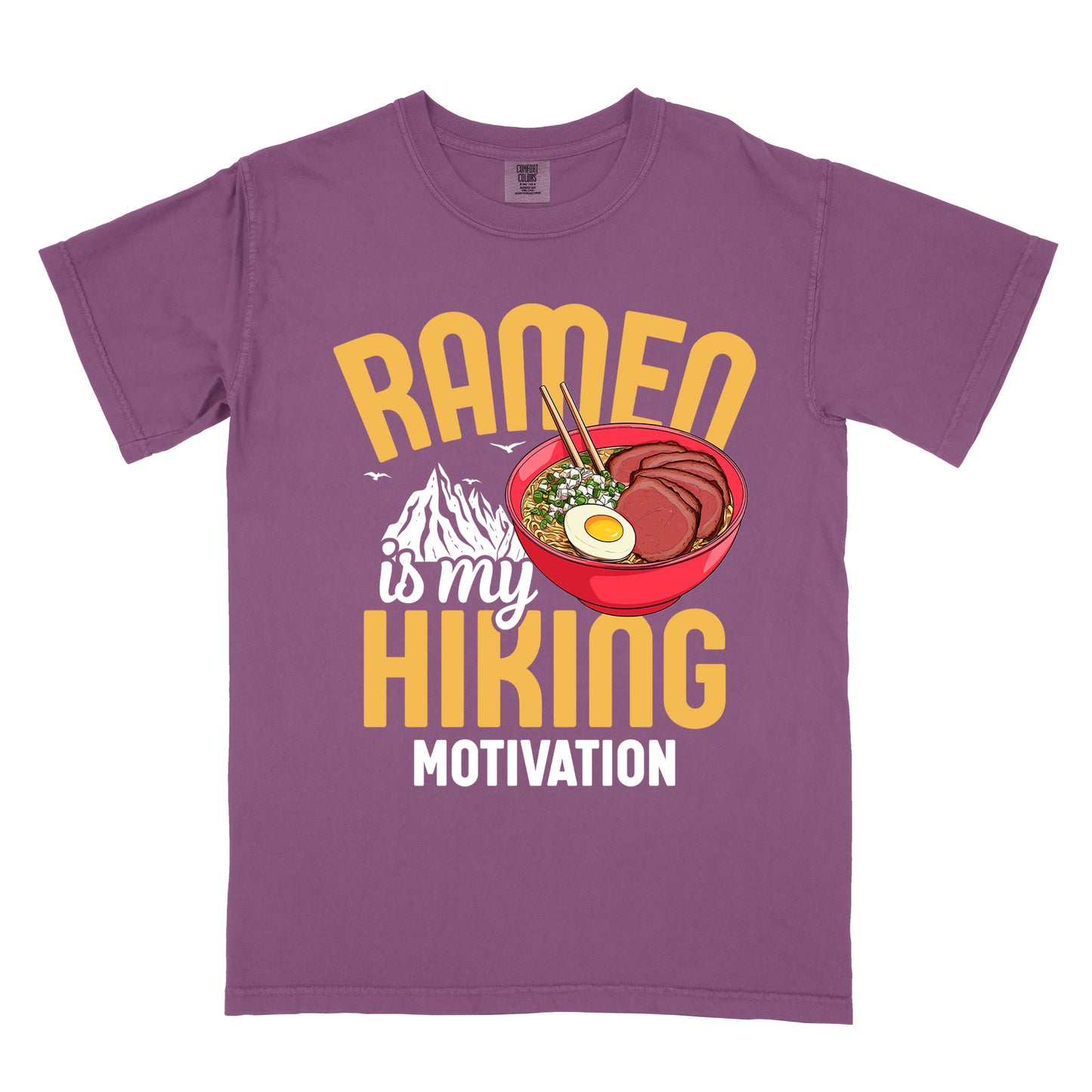 Berry (Dark Violet) t-shirt with "RAMEN is my HIKING MOTIVATION" text design. "RAMEN" and "HIKING" appear in large yellow letters, with "is my" in white script and "MOTIVATION" in white capitals. The design features a colorful illustration of a red ramen bowl with sliced meat, egg, green onions, and chopsticks. A white mountain silhouette appears between "RAMEN" and "HIKING", with small bird silhouettes nearby.