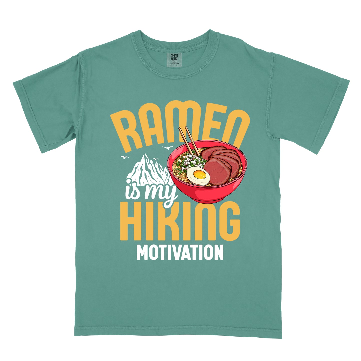 Light Green t-shirt with "RAMEN is my HIKING MOTIVATION" text design. "RAMEN" and "HIKING" appear in large yellow letters, with "is my" in white script and "MOTIVATION" in white capitals. The design features a colorful illustration of a red ramen bowl with sliced meat, egg, green onions, and chopsticks. A white mountain silhouette appears between "RAMEN" and "HIKING", with small bird silhouettes nearby.