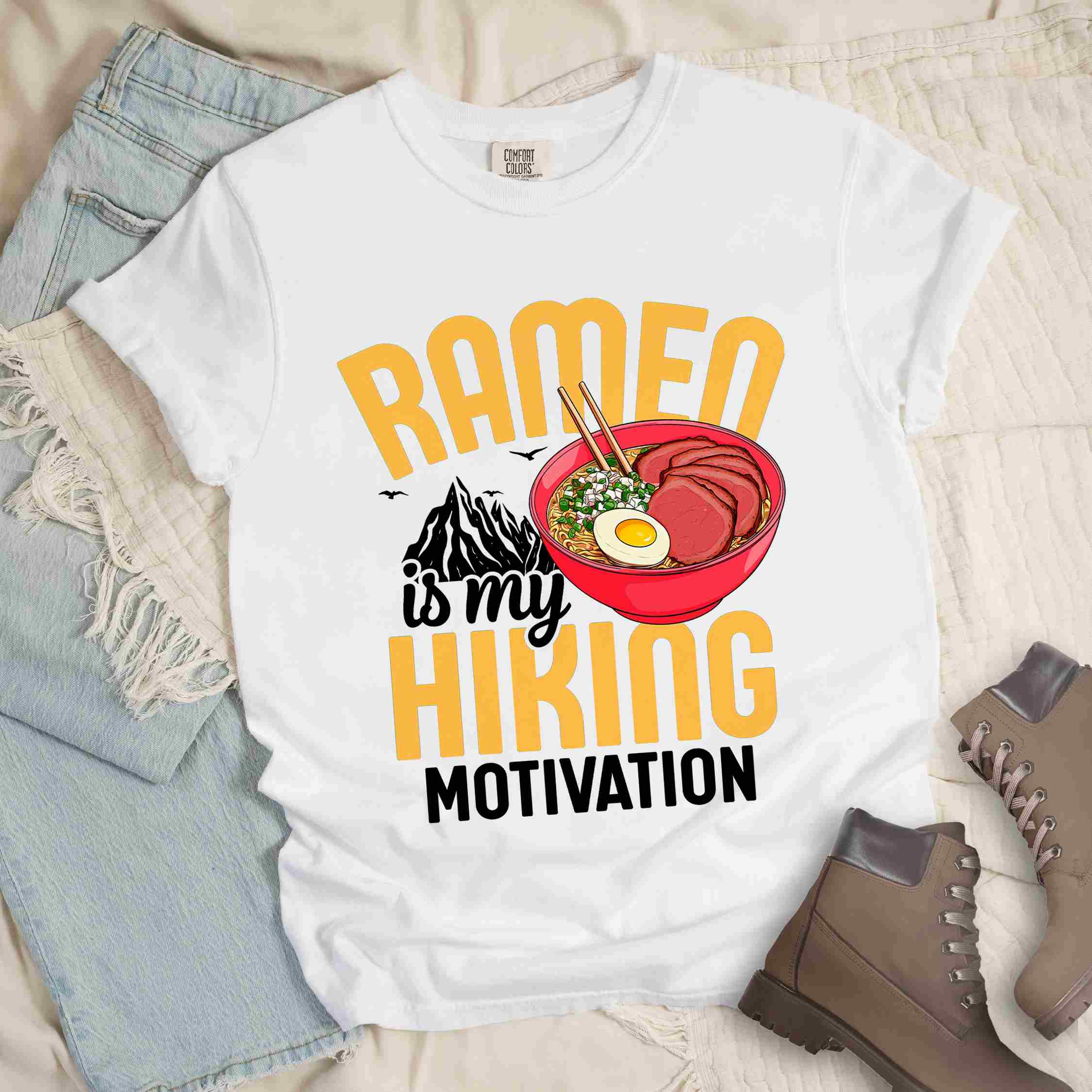 White “Ramen is my Hiking motivation” colored vintage tee with bold text, mountain, Illustration of hot ramen. Perfect tee for foodie craving for a bowl of ramen,