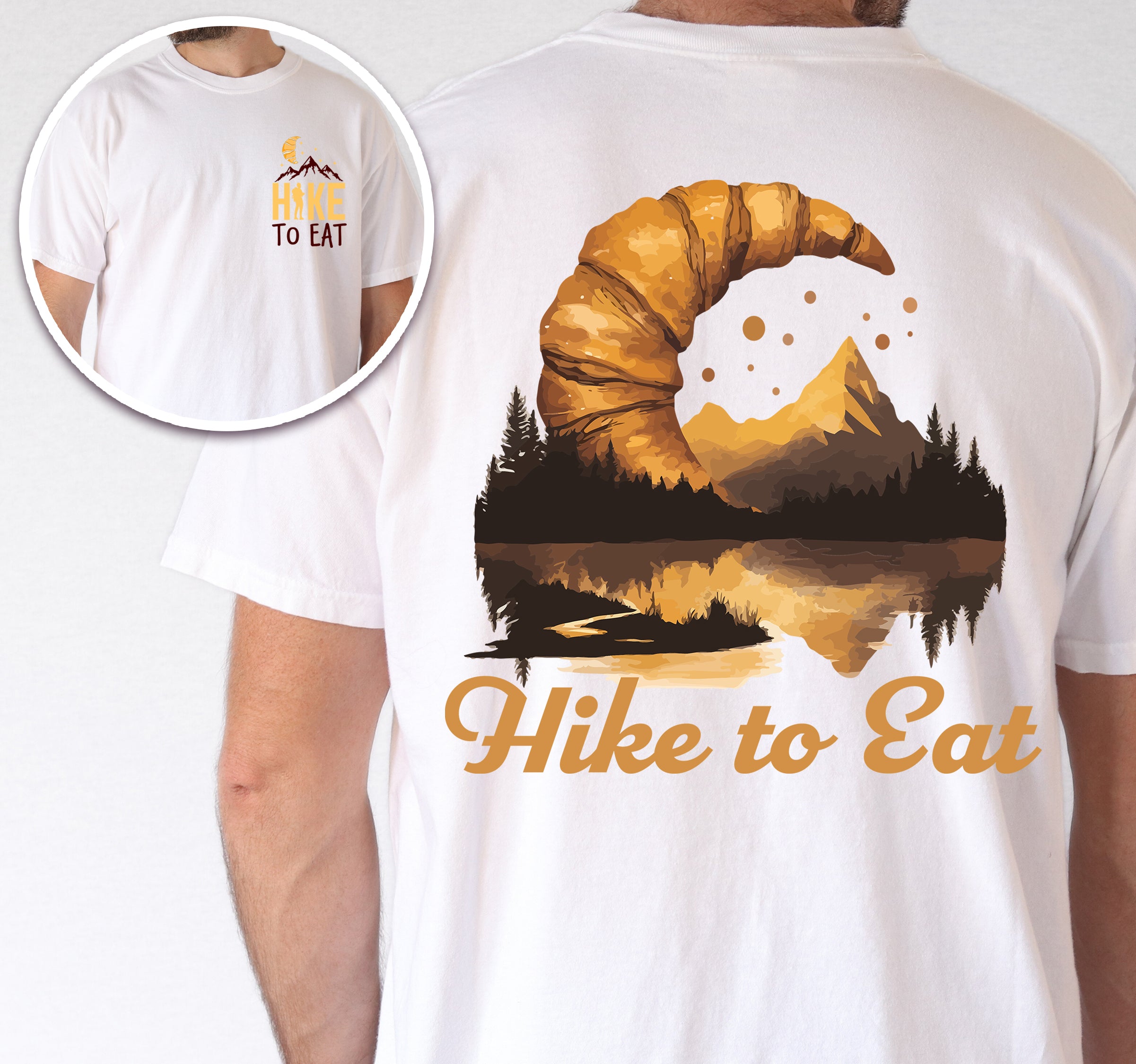 White Hike to Eat t-shirt front and back view showing small chest logo and large back design featuring golden croissant filled with sunset mountain lake landscape, pine trees, and reflected peaks.