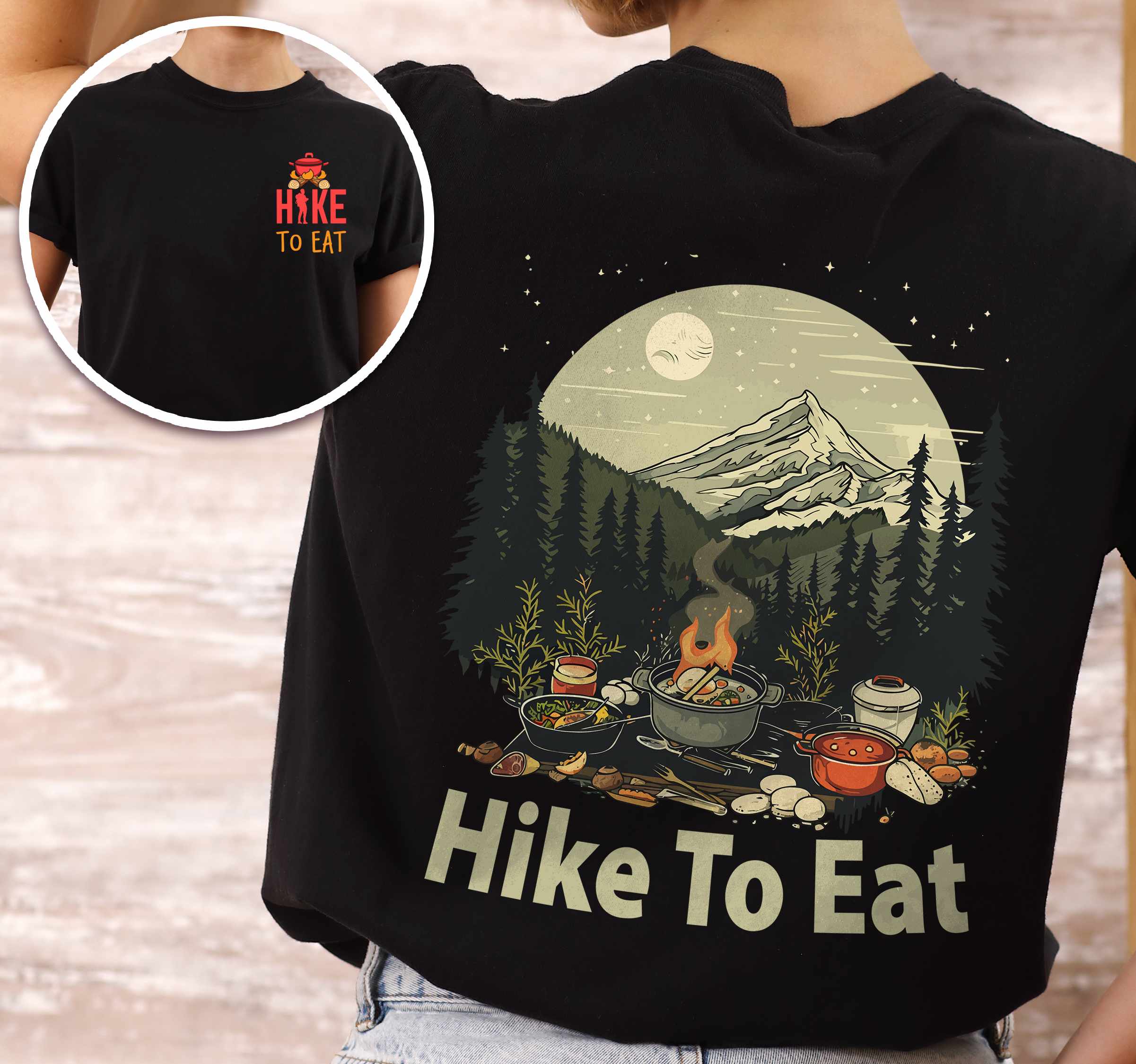 Woman wearing black "Hike to Eat" text in bold lettering front and back design, mountains, birds, illustrated camping feast, and backpacker for campfire cooking enthusiasts.