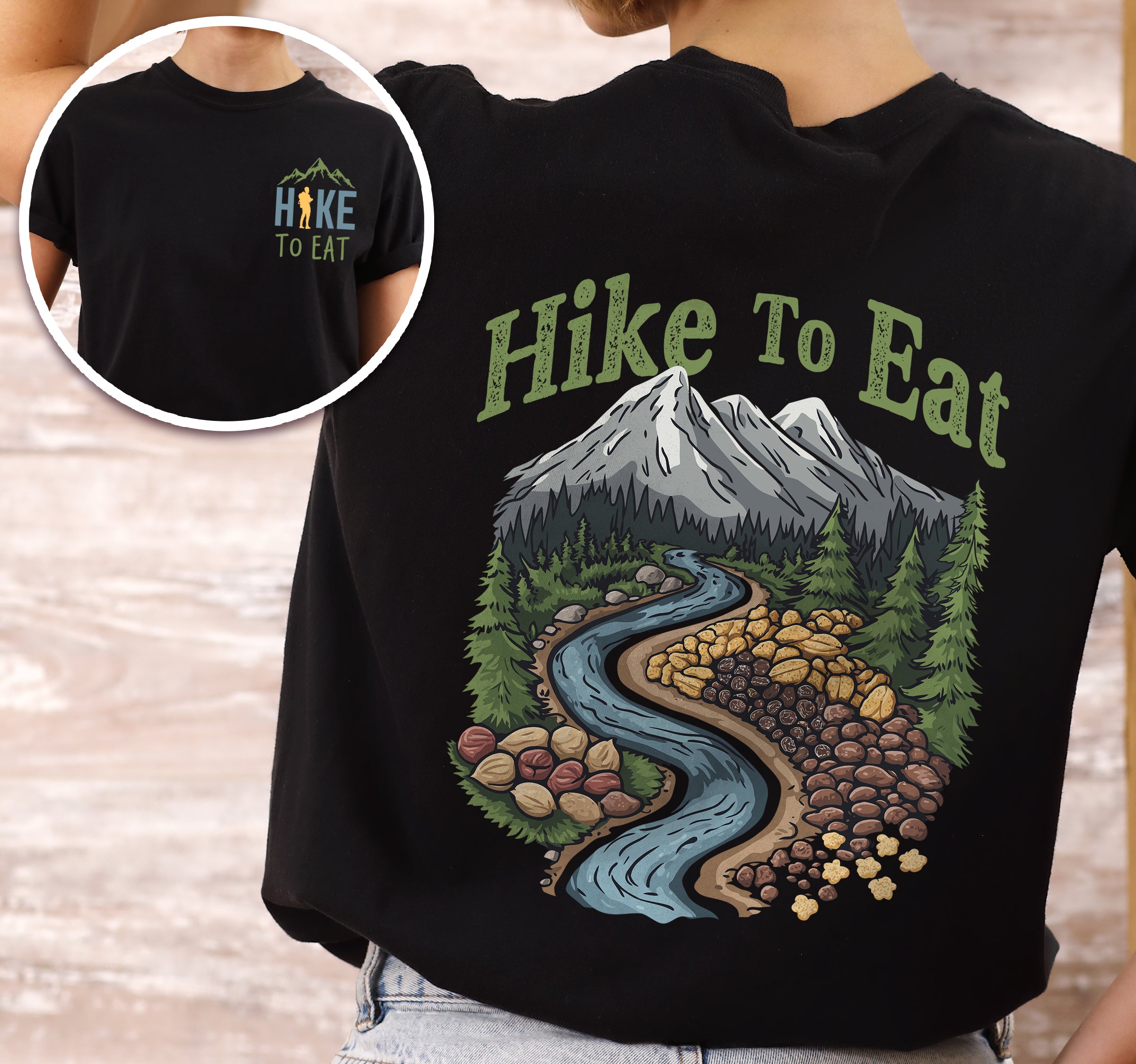 Black Hike to Eat t-shirt front and back view showing small colorful chest logo and large back design featuring winding river through mountain landscape filled with trail mix nuts, dried fruits, and snacks