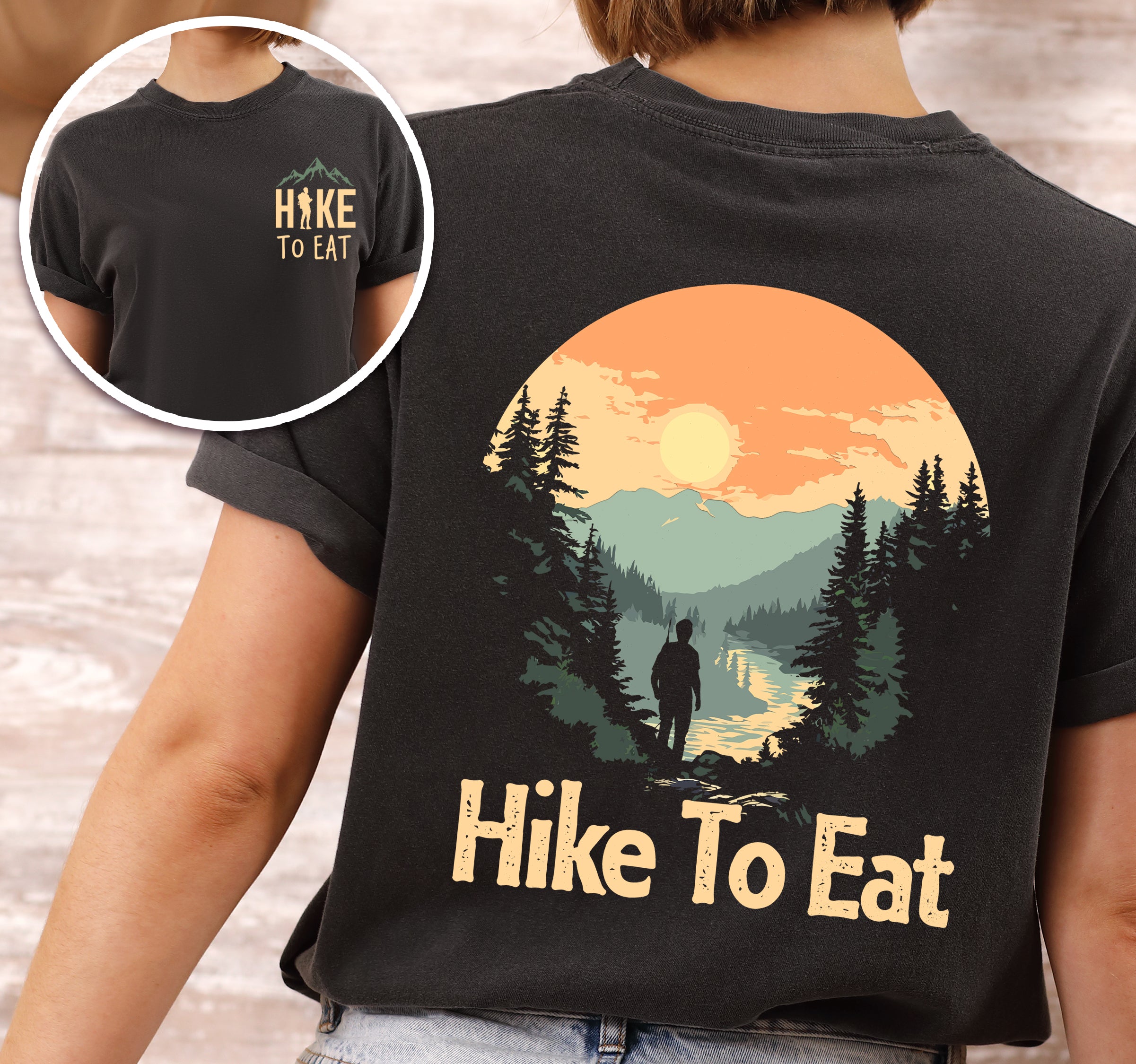 Graphite (Deep Gray) Hike to Eat t-shirt front and back view showing small yellow chest logo and large back design featuring circular sunset mountain scene with hiker silhouette by lake, pine trees, and orange sky