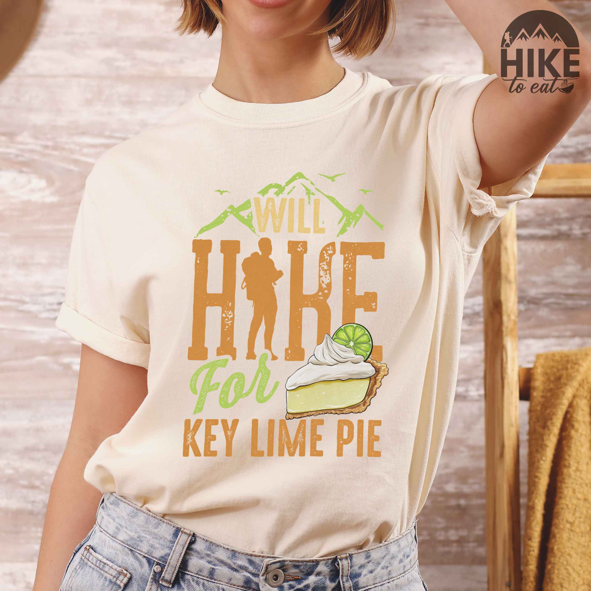 Woman wearing ivory "Will Hike for Key Lime Pie" colored vintage tee with bold typography, illustrated slice of key lime pie, mountains, birds, and backpacker with the sweet tooth.