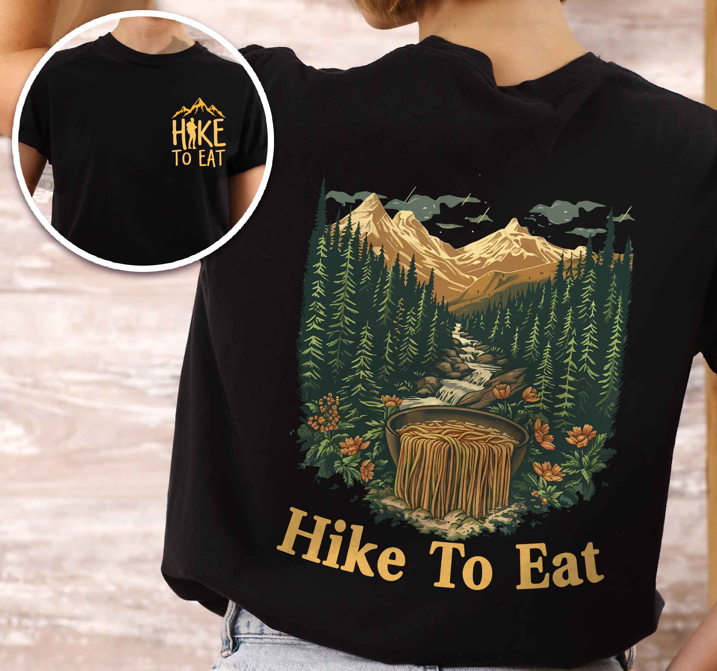 Woman wearing black "Hike to Eat" text in cream lettering front and back design, mountains, birds, illustrated bowl of ramen noodles, and backpacker for ramen lovers.