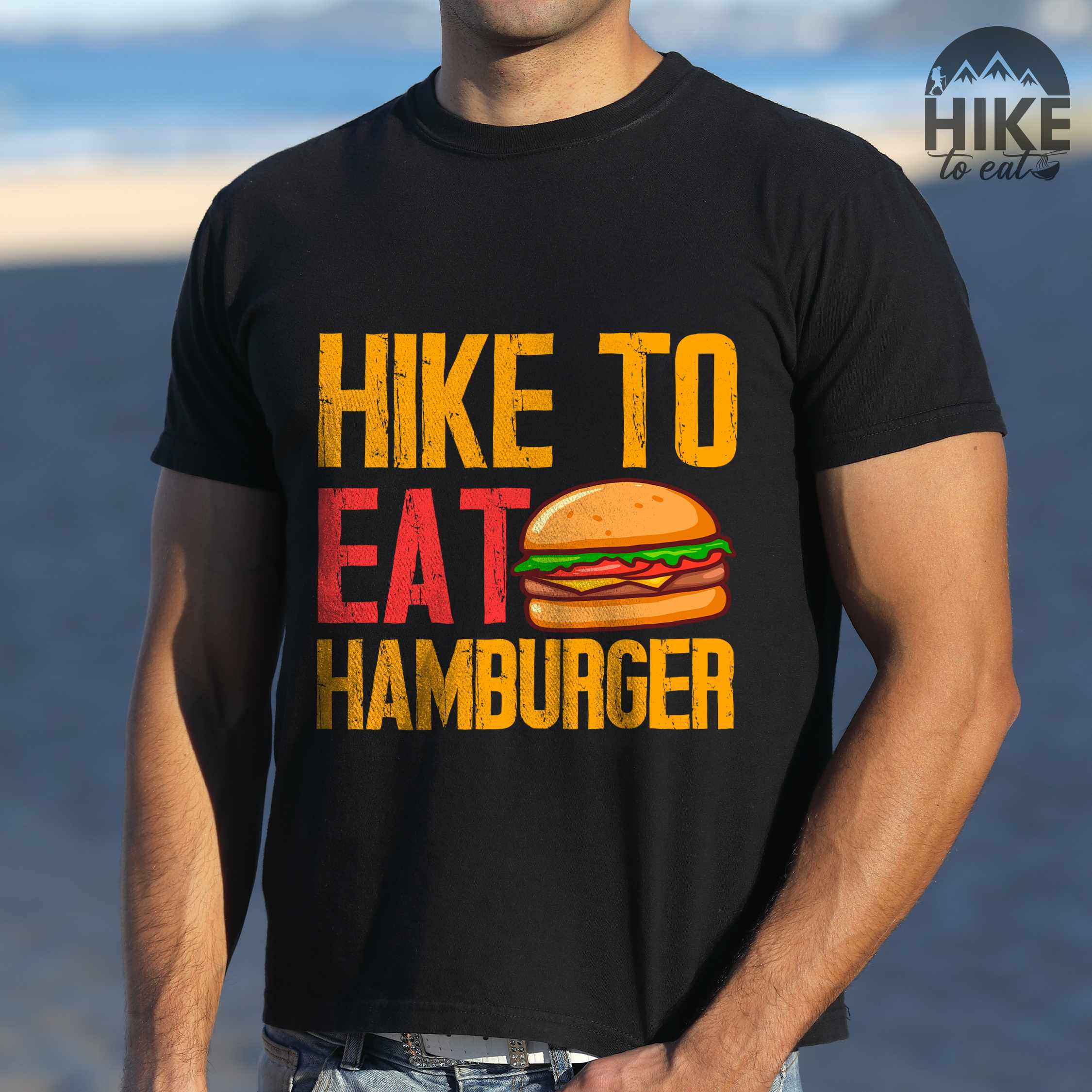 Man wearing black "Hike to eat Hamburger" colored vintage tee with bold typography, juicy cheese hamburger illustration, perfect for the hamburger enthusiasts.