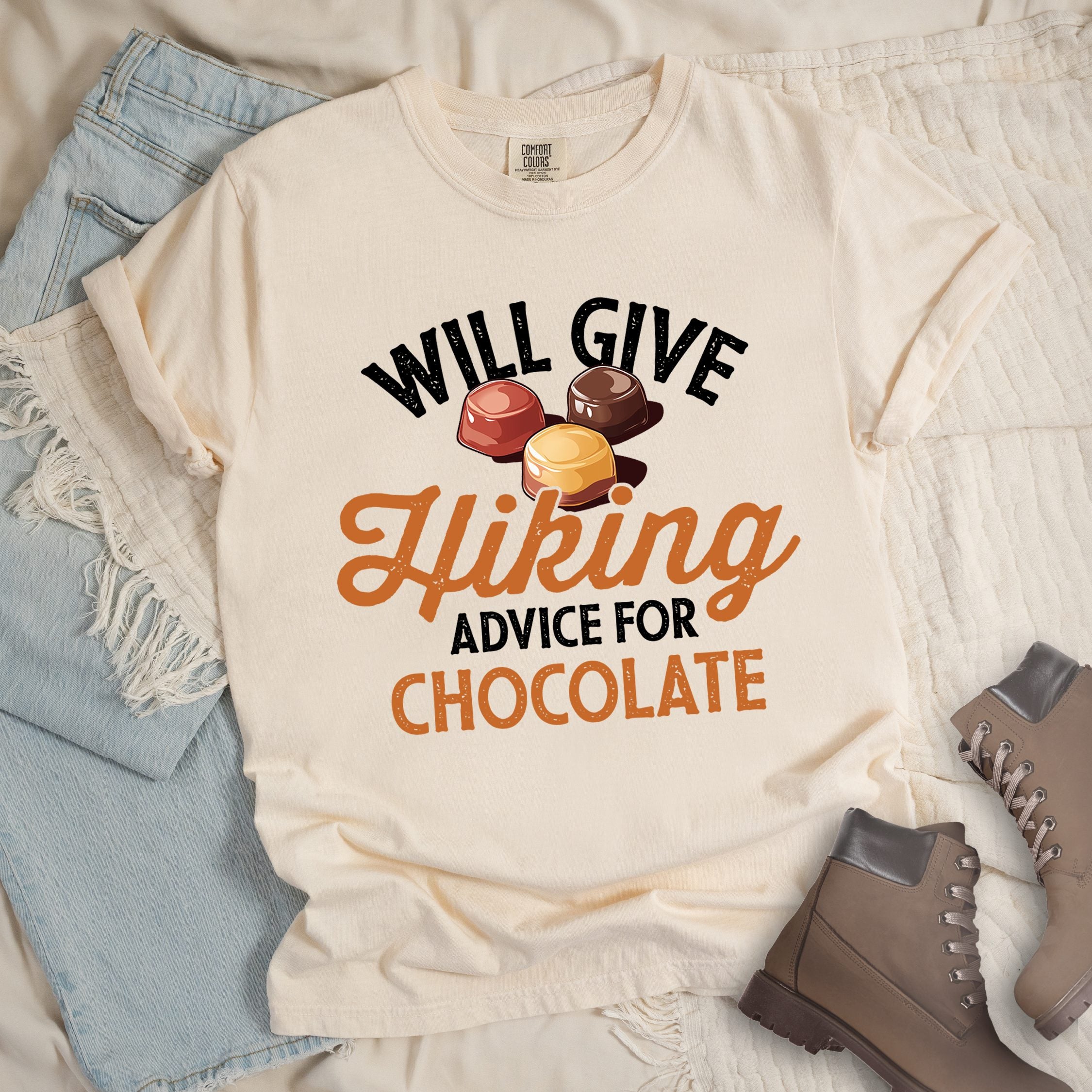 Ivory shirt with the text “Will Give Hiking Advice for Chocolate” featuring stylized lettering and an illustration of assorted chocolate candies.