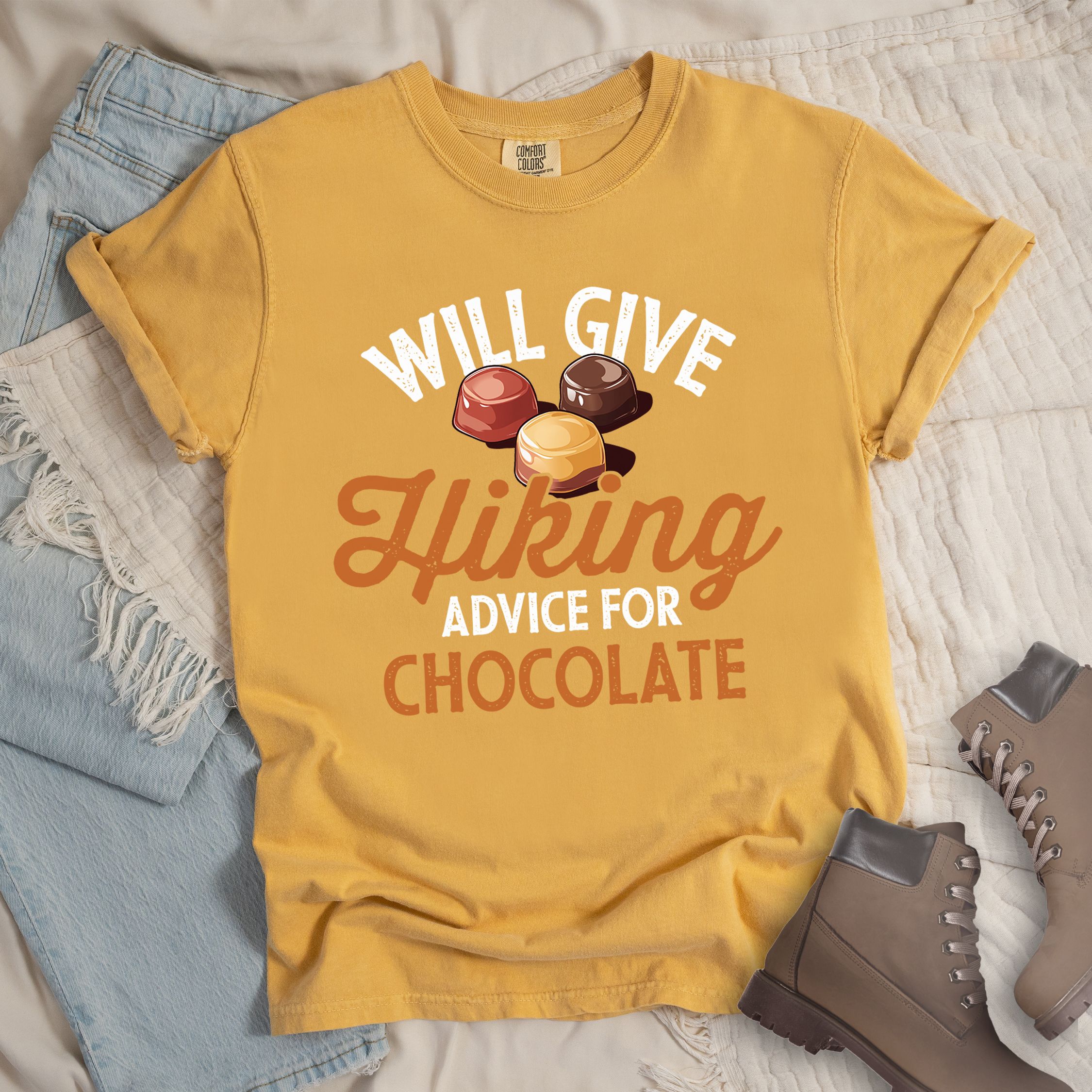 Yellow shirt with the text “Will Give Hiking Advice for Chocolate” featuring stylized lettering and an illustration of assorted chocolate candies.