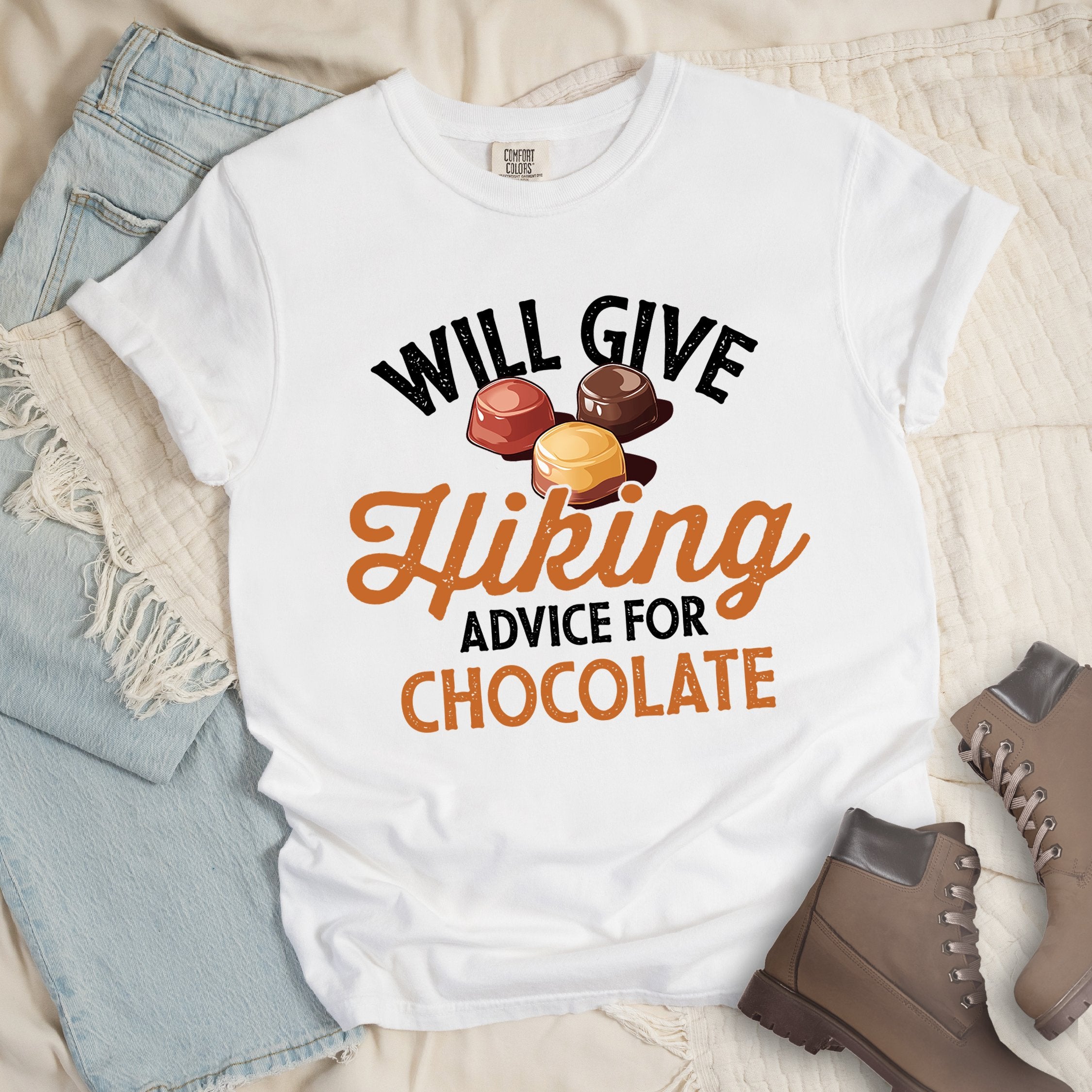White shirt with the text “Will Give Hiking Advice for Chocolate” featuring stylized lettering and an illustration of assorted chocolate candies.