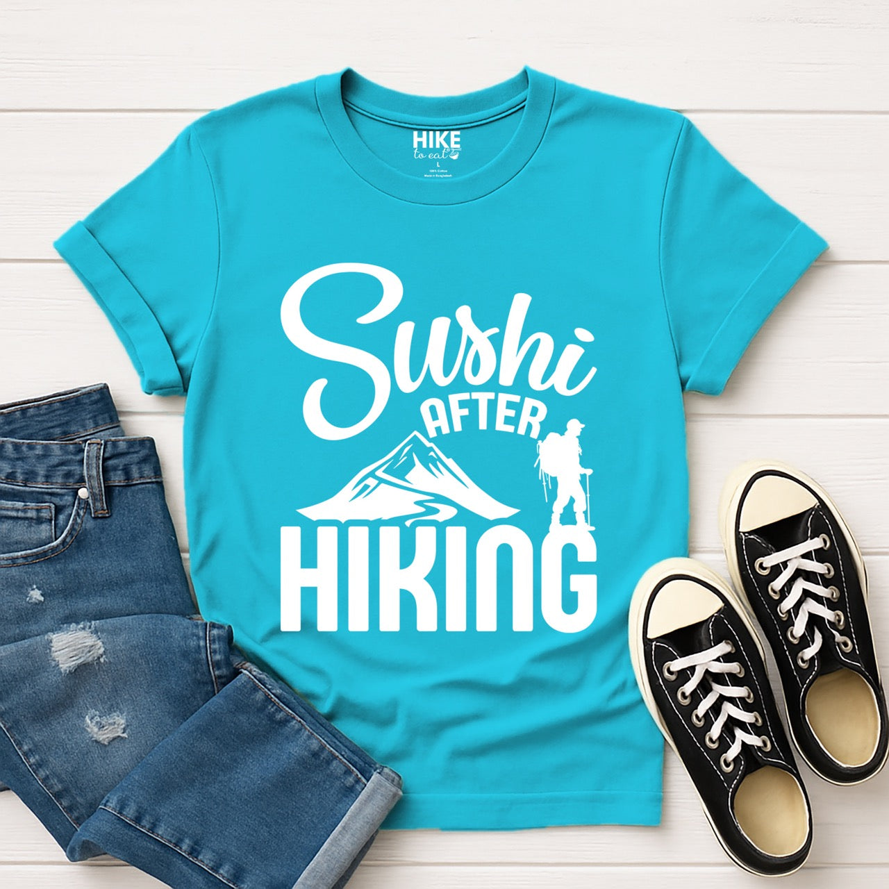 tropical blue Sushi after Hiking statement tee with elegant script typography, mountain peaks, and hiker silhouette for Japanese food-loving outdoor enthusiasts , foodies and hikers with jeans and shoes