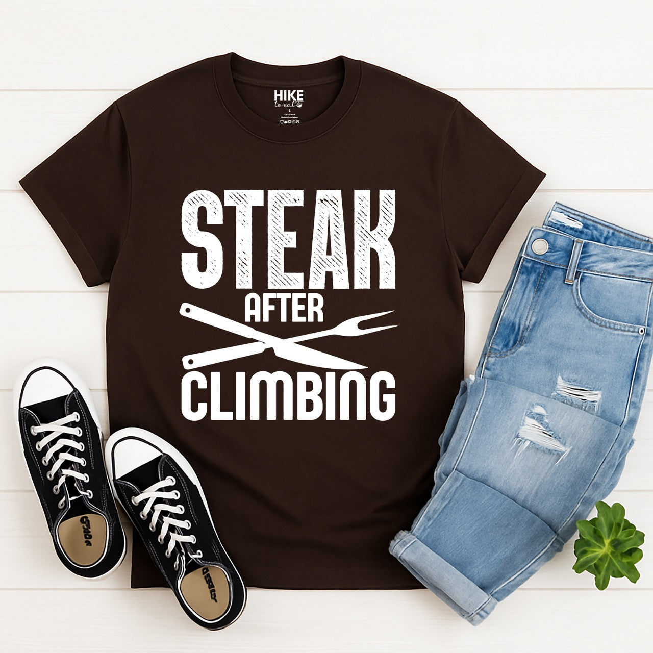 dark chocolate (brown) Steak after Climbing statement tee with distressed bold typography and crossed knife and fork for rock climbing and steak-loving outdoor enthusiasts, hikers and foodies with jeans and shoes