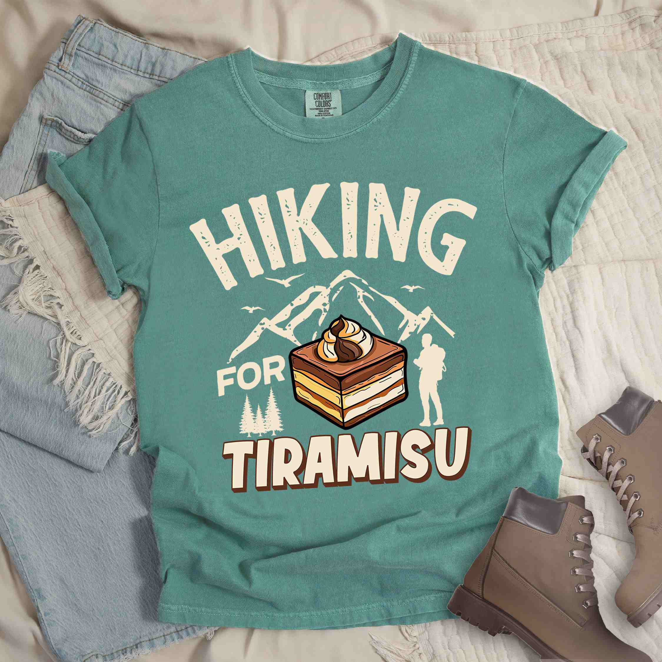 Light green "Hiking for Tiramisu" colored vintage tee with bold typography, mountains, illustrated a serving of Tiramisu, and backpackers with a sweet tooth.