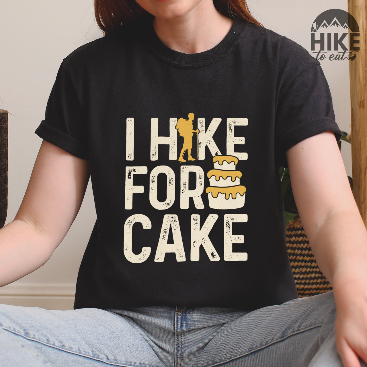Woman wearing black I Hike for Cake vintage statement tee with distressed typography, hiker silhouette, and layered cake illustration on Comfort Colors shirt for dessert-loving outdoor enthusiasts