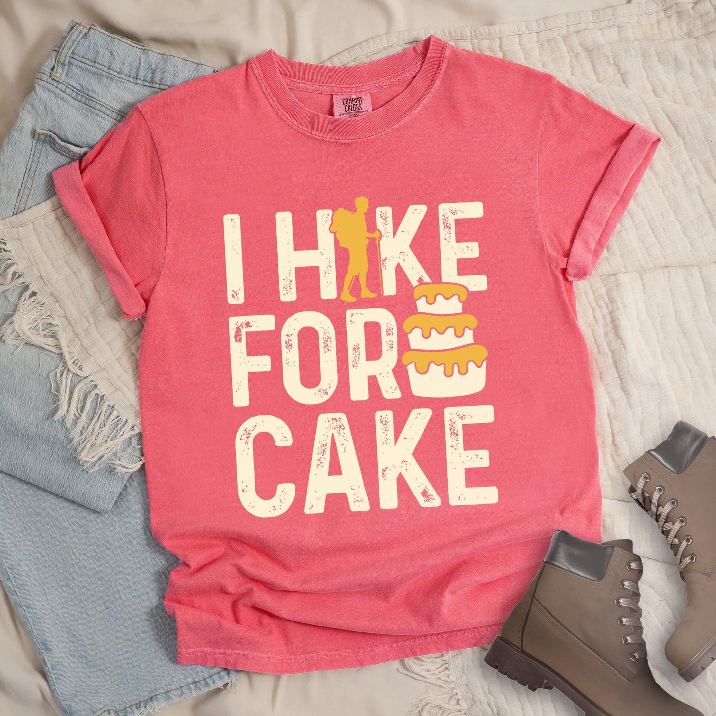 Pink shirt with the bold text “I Hike for Cake” and an illustration of a layered cake with frosting.