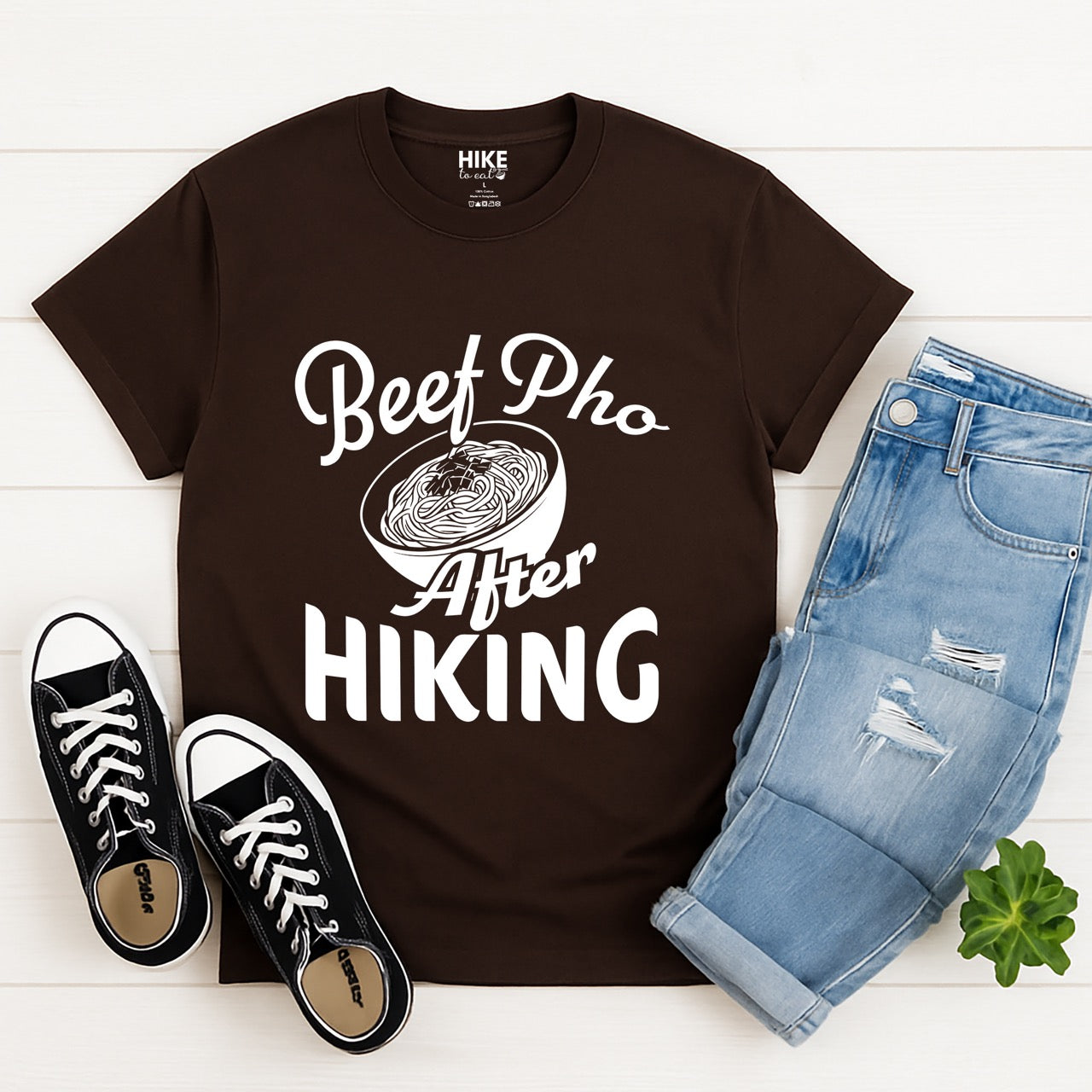 Chocolate Brown Beef Pho After Hiking statement tee with flowing script typography, bold lettering, and detailed pho bowl illustration for Vietnamese food-loving outdoor enthusiasts, hikers and foodies with pants and shoes