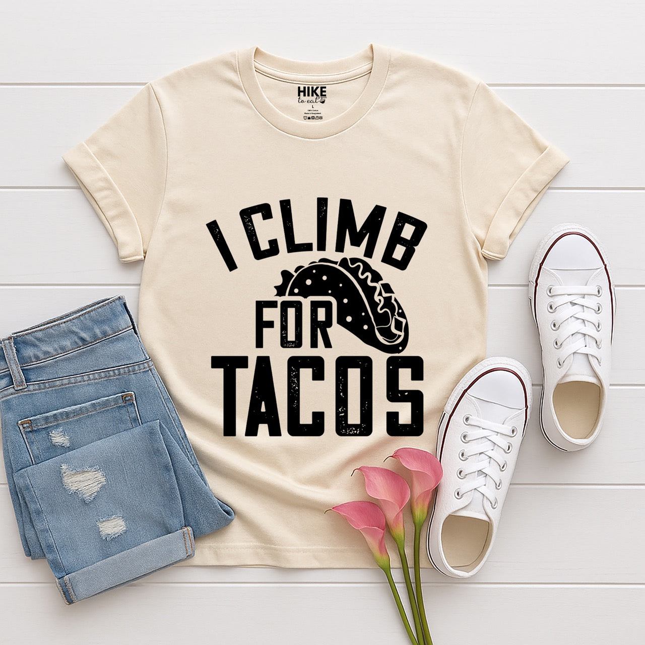 Natural (beige) l I climb for Tacos statement tee with bold distressed curved typography and detailed taco illustration for Mexican food-loving rock climbers and nature hikers laid flat with pants and shoes