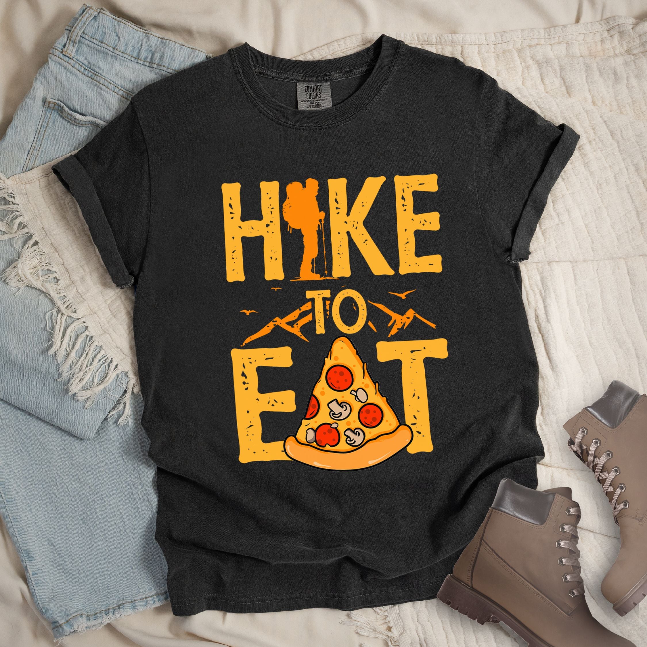 Dark grey shirt with a Hiking design of a slice of pizza and shows 'Hike To Eat' phrase in bold text