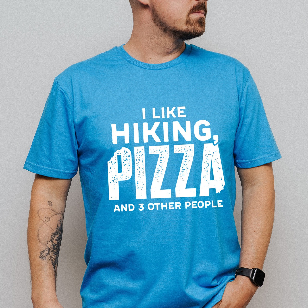 Man wearing Saphire Motivated by Wontons statement tee with bold distressed typography, mountain peaks, pine trees, and wonton illustration for Chinese food-loving outdoor enthusiasts, hikers and foodies