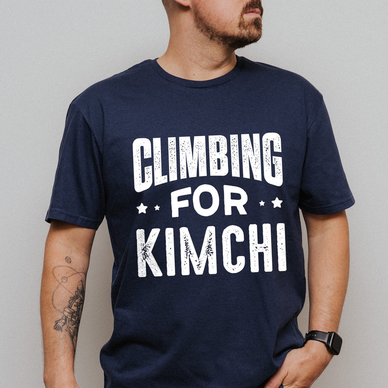 Man wearing Navy Rock climbing enthusiast gift shirt Climbing For Kimchi with bold curved distressed typography and decorative star accents for Korean food lovers and outdoor athletes who crave fermented vegetables after mountain adventures for climbers, hikers and foodies