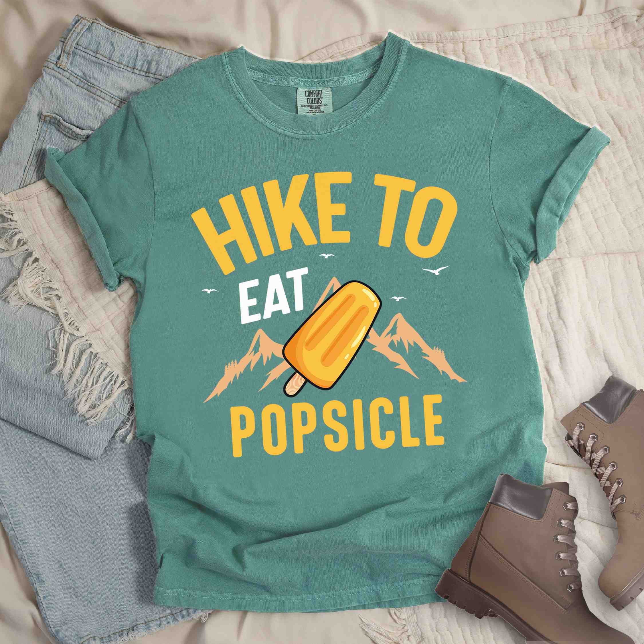 Light green  "Hike to Eat Popsicle" colored vintage tee with bold typography, mountains, illustrated flavored popsicle, and backpackers with a sweet tooth.