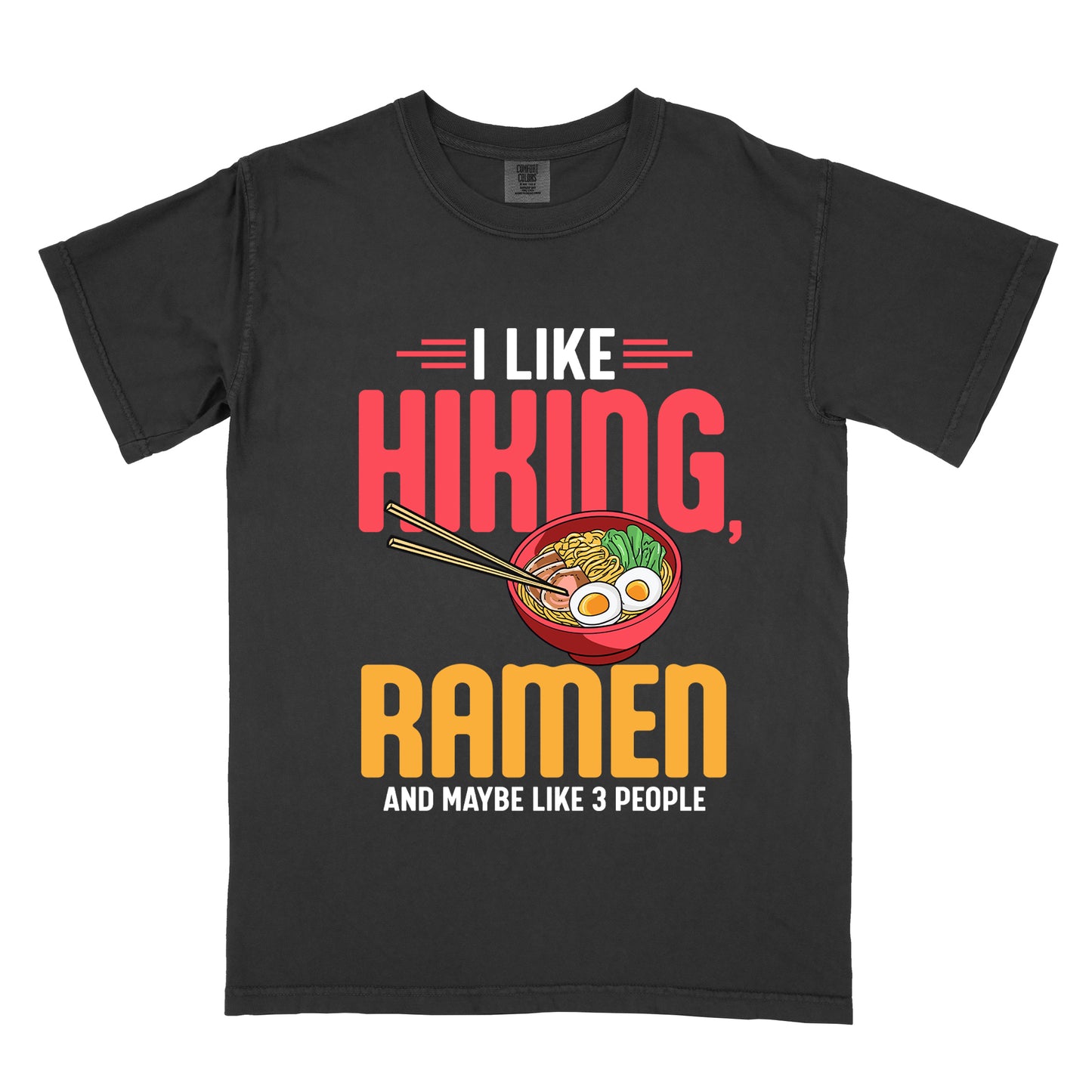 Black t-shirt with text "I LIKE HIKING, RAMEN AND MAYBE LIKE 3 PEOPLE". "I LIKE" appears in white at the top with red decorative lines, "HIKING," in large red letters, "RAMEN" in yellow/orange, and "AND MAYBE LIKE 3 PEOPLE" in white at the bottom. Between "HIKING" and "RAMEN" is a colorful illustration of a red ramen bowl with noodles, egg, and vegetables, with chopsticks.