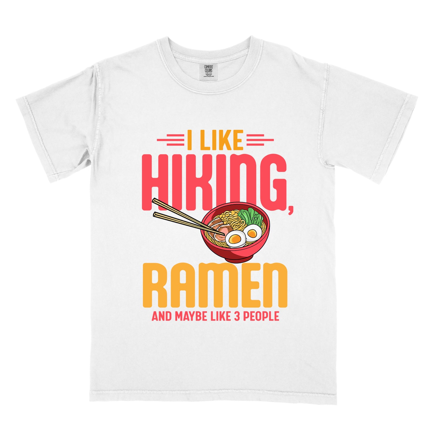 White t-shirt with text "I LIKE HIKING, RAMEN AND MAYBE LIKE 3 PEOPLE". "I LIKE" appears in orange at the top with red decorative lines, "HIKING," in large red letters, "RAMEN" in yellow/orange, and "AND MAYBE LIKE 3 PEOPLE" in red at the bottom. Between "HIKING" and "RAMEN" is a colorful illustration of a red ramen bowl with noodles, egg, and vegetables, with chopsticks.