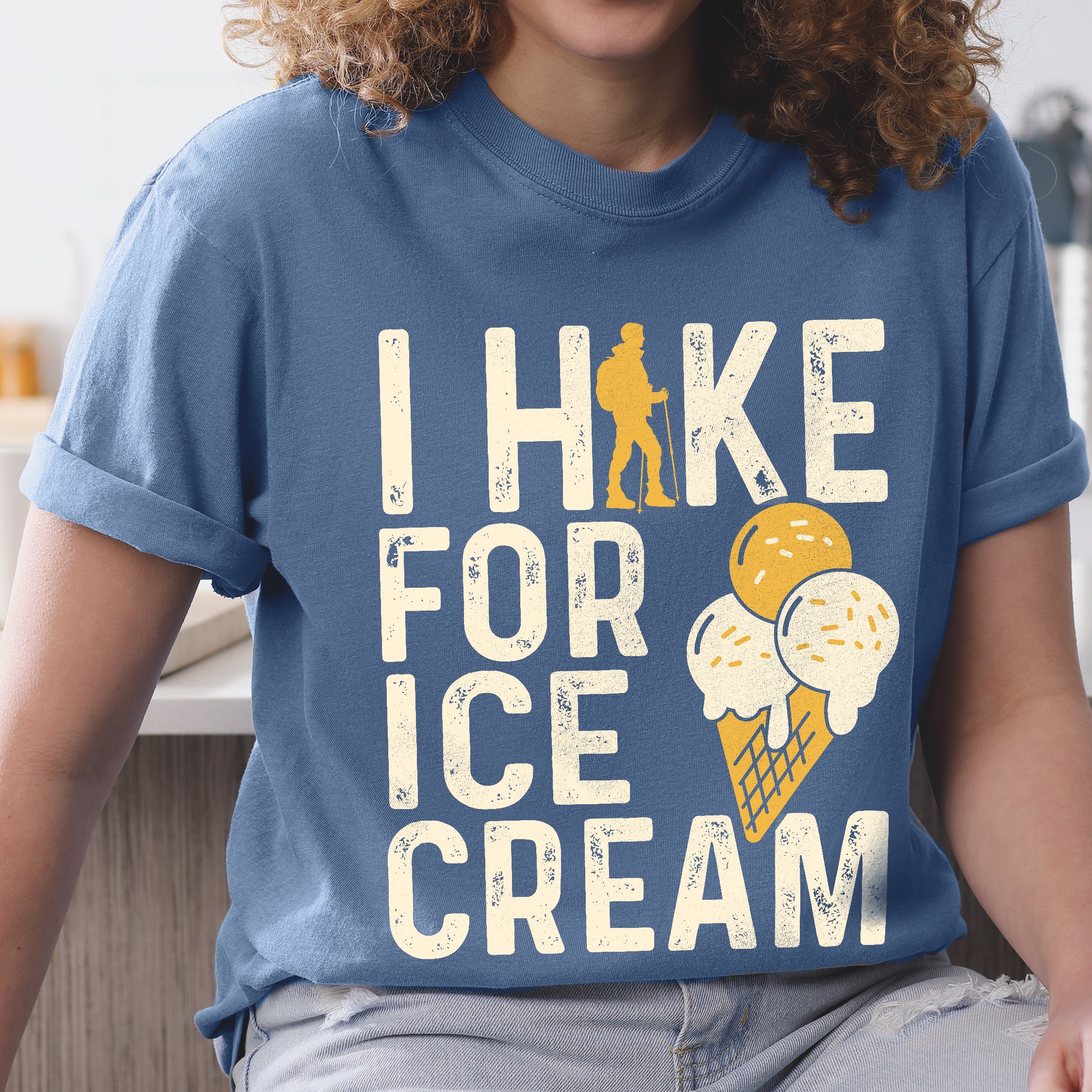 woman wearing blue jean (blue) I Hike for Ice Cream statement tee with vintage distressed typography, hiker silhouette, and double-scoop ice cream cone illustration on Comfort Colors shirt for dessert-loving outdoor enthusiasts and hikers