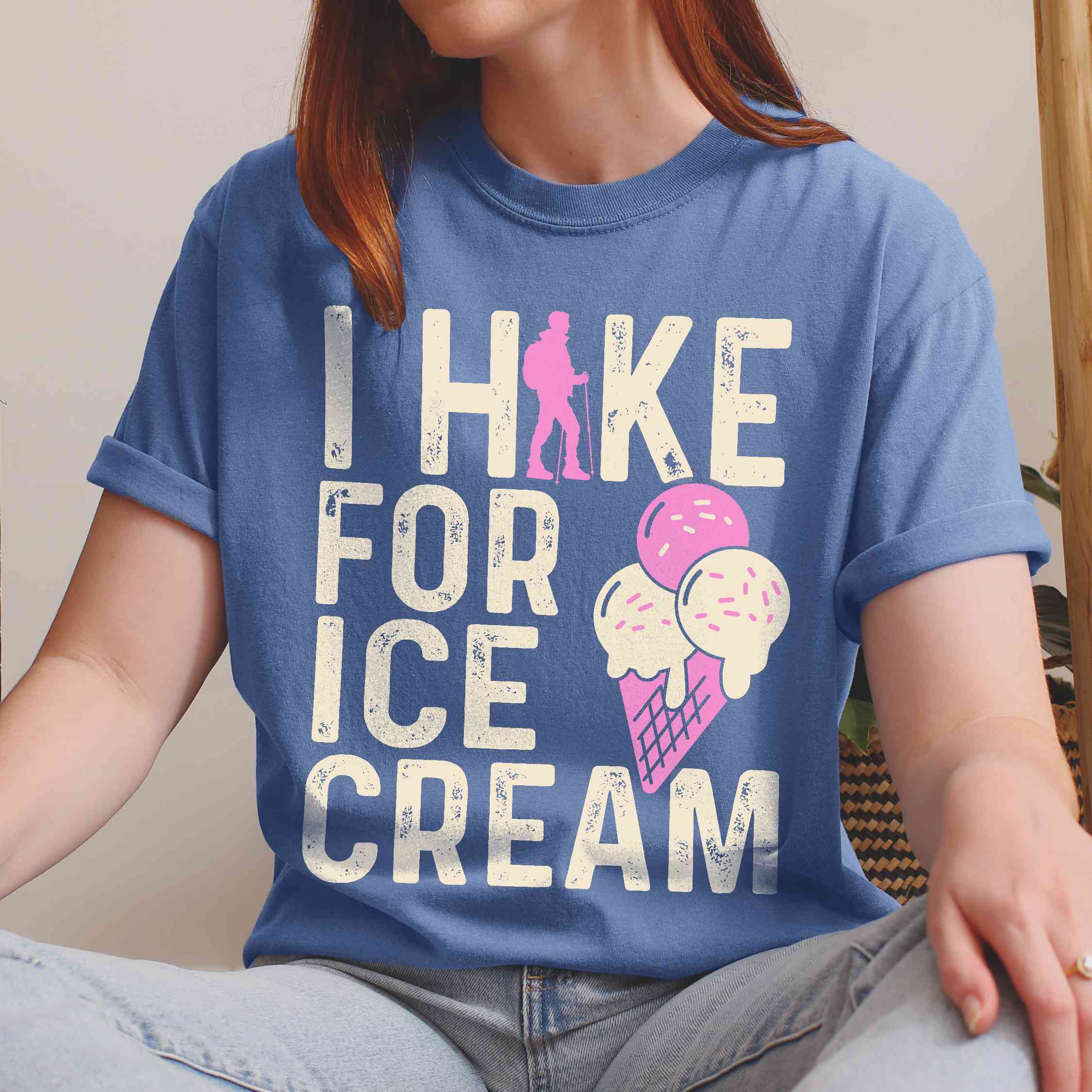 Woman wearing blue jean I Hike for Ice Cream statement tee with vintage distressed typography, hiker silhouette, and double-scoop ice cream cone illustration on Comfort Colors shirt for dessert-loving outdoor enthusiasts and hikers