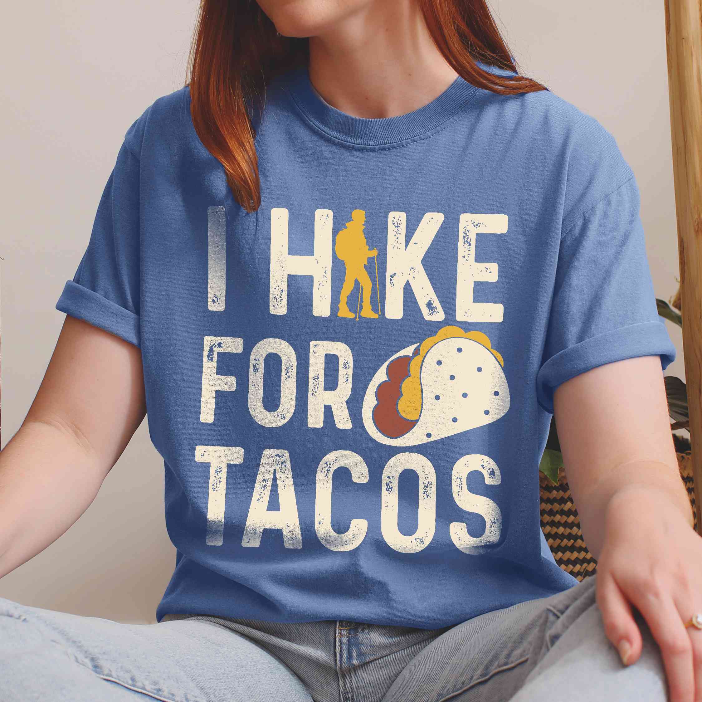 Woman wearing blue jean colored vintage tee with 'I Hike for Tacos' text in cream lettering, illustrated taco, and backpacker for taco lovers