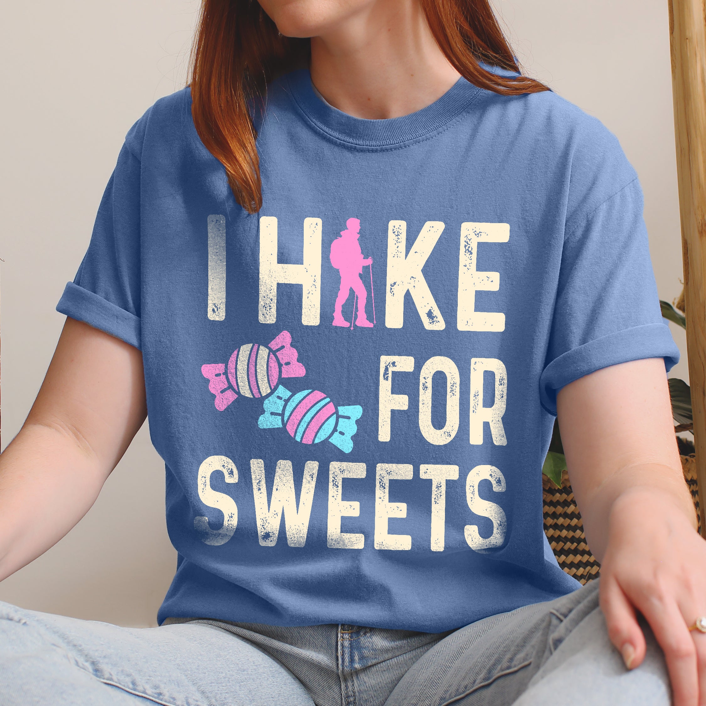 Blue Jean (Denim Blue) graphic t-shirt with 'I Hike for Sweets' text in cream lettering featuring pink hiker silhouette and colorful striped candy illustrations in pink and blue