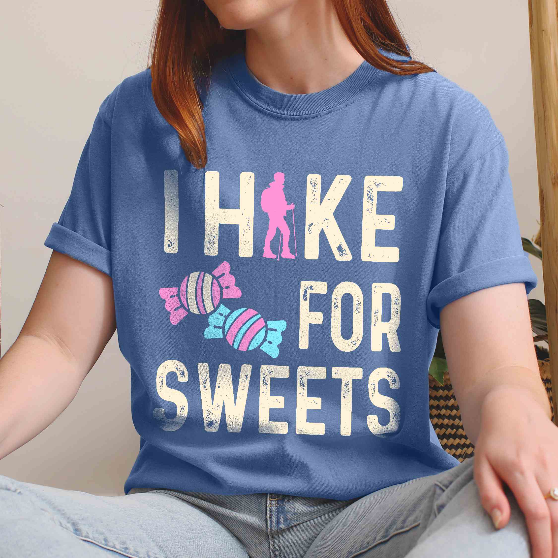Woman wearing blue jean 'I Hike for Sweets' text in cream lettering, illustrated pieces of candies, and backpacker for candy lovers