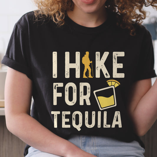 Black graphic t-shirt with 'I Hike for Tequila' text in cream lettering featuring orange hiker silhouette and tequila shot glass illustration with lime garnish.