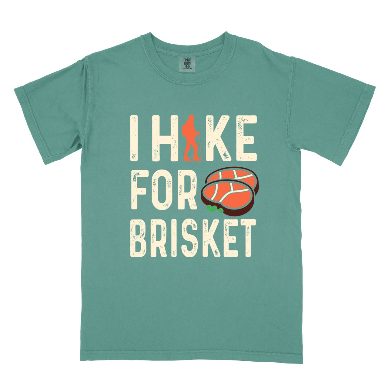 Light Green BBQ brisket lover statement tee I Hike for Brisket with distressed brown typography character silhouette with trekking pole and illustrated sliced smoked brisket with herb garnish on vintage Comfort Colors shirt for food motivated adventurers for hikers and foodies. 