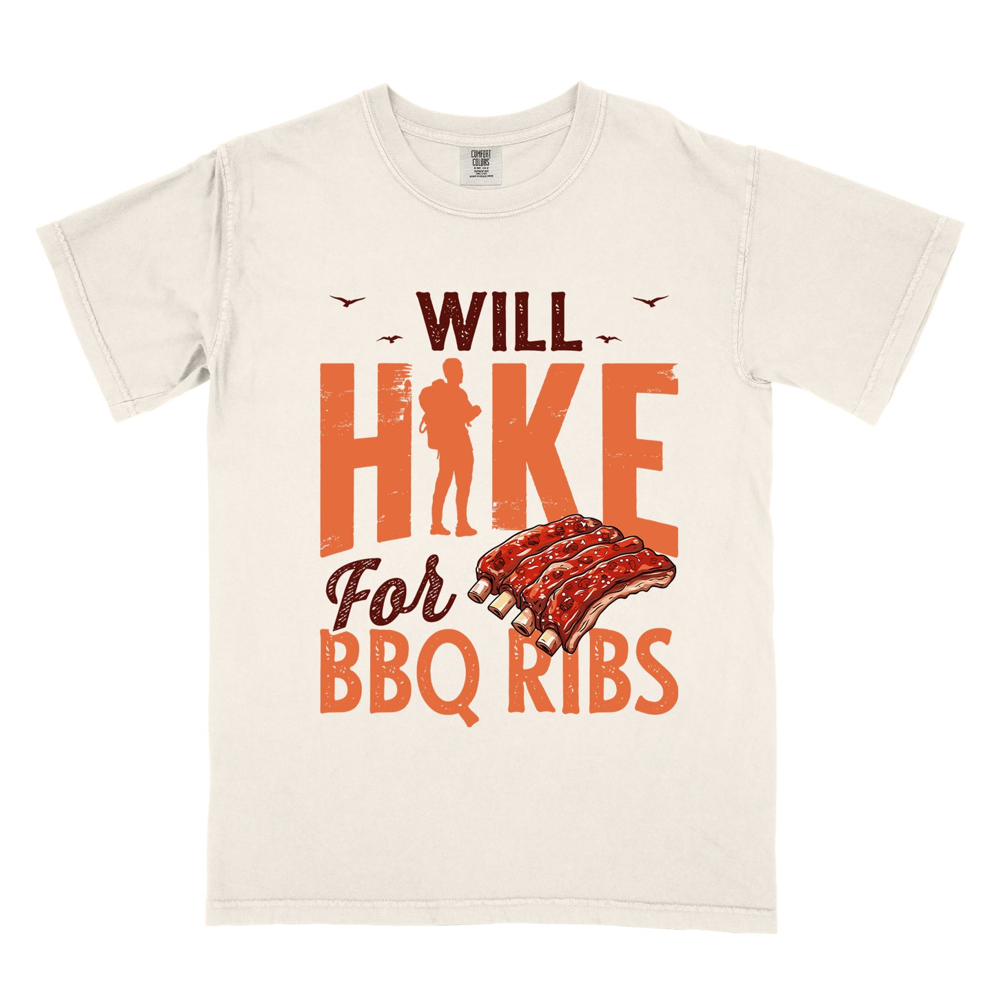 Ivory (Cream White) t-shirt with text "WILL HIKE For BBQ RIBS". "WILL" appears in deep brown-red distressed letters at the top with small bird silhouettes. "HIKE" is in large orange distressed text with a hiker silhouette replacing the letter "I". "For" appears in deep brown-red script, and "BBQ RIBS" in matching orange at the bottom. Between "For" and "BBQ RIBS" is an illustration of a rack of barbecue ribs with exposed bones.