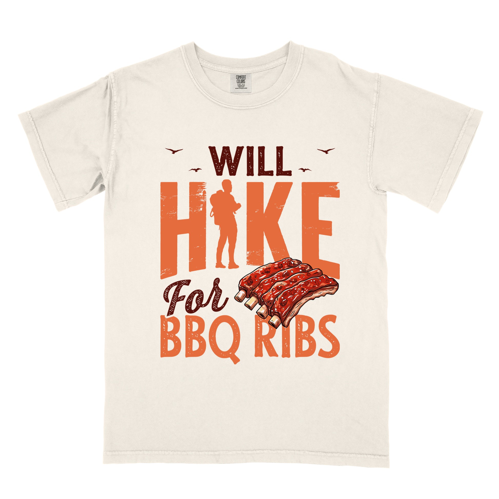 Ivory (Cream White) t-shirt with text "WILL HIKE For BBQ RIBS". "WILL" appears in deep brown-red distressed letters at the top with small bird silhouettes. "HIKE" is in large orange distressed text with a hiker silhouette replacing the letter "I". "For" appears in deep brown-red script, and "BBQ RIBS" in matching orange at the bottom. Between "For" and "BBQ RIBS" is an illustration of a rack of barbecue ribs with exposed bones.