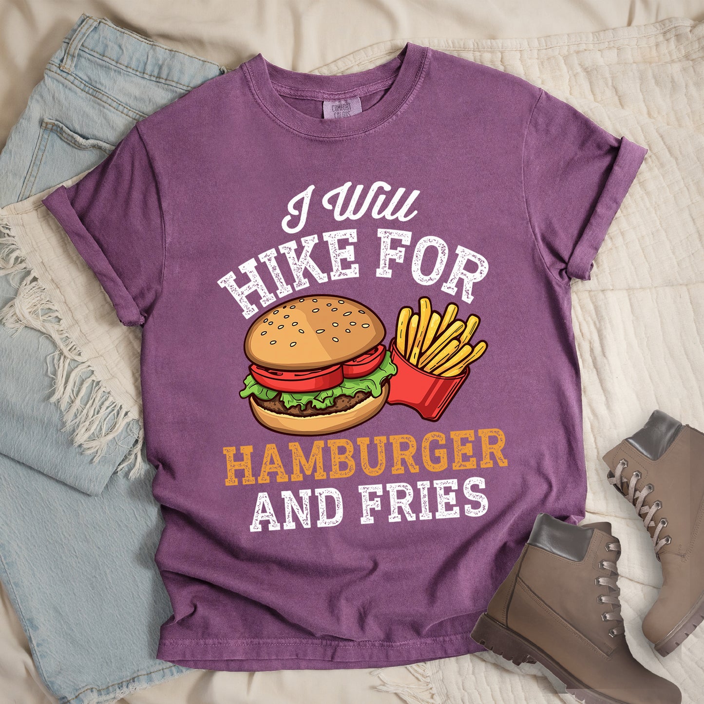 Berry (Dark Violet) t-shirt with white distressed text reading "I Will HIKE FOR HAMBURGER AND FRIES". The words "I Will" appear in white script at the top, "HIKE FOR" in white block letters, "HAMBURGER" in gold/orange, and "AND FRIES" in white at the bottom. Center illustration shows a detailed hamburger with bun, patty, lettuce, and tomato next to a red container of yellow french fries.