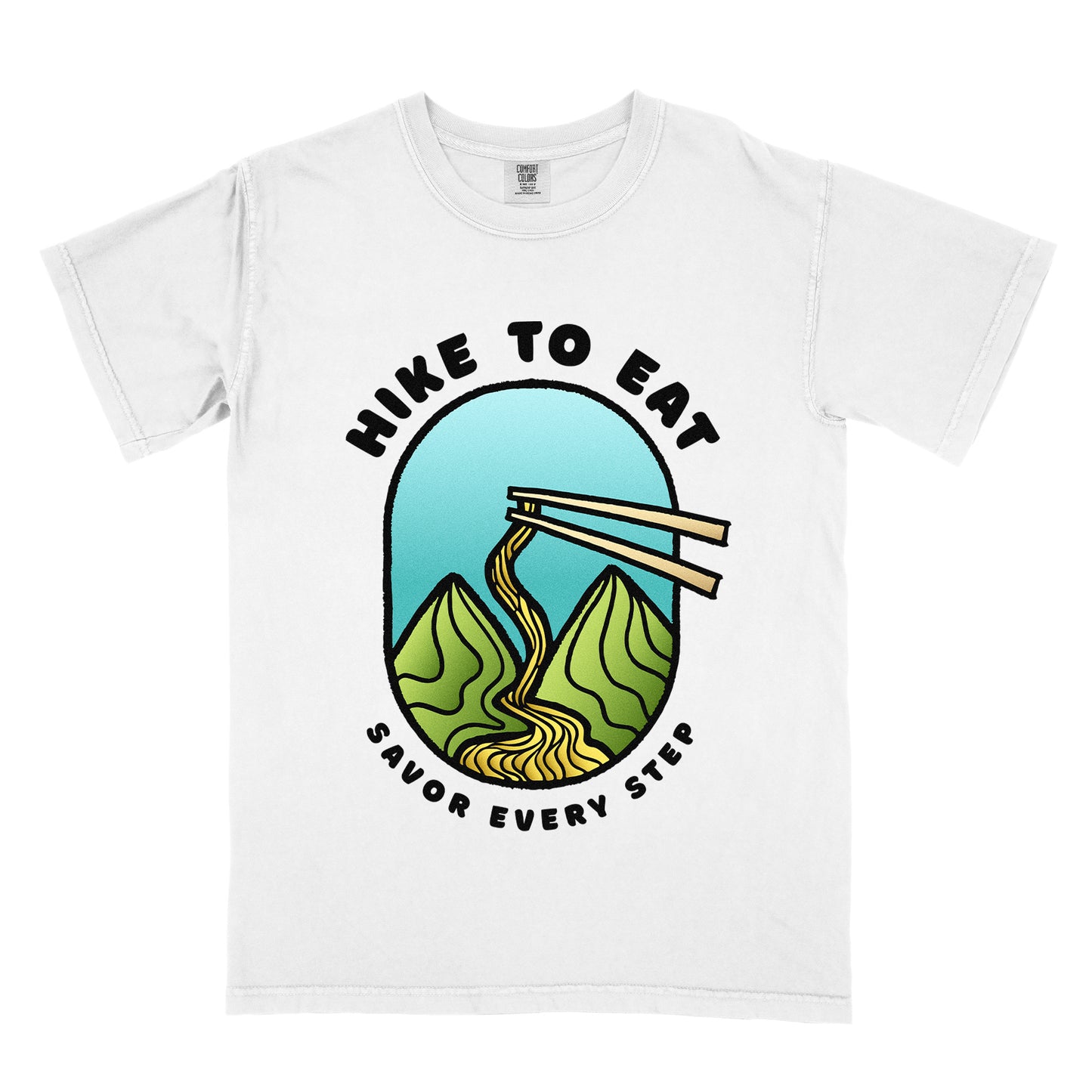 A white t-shirt with black text "HIKE TO EAT" arched at the top and "SAVOR EVERY STEP" at the bottom. The center features an oval graphic with a turquoise blue sky background, green mountain peaks, and chopsticks lifting ramen noodles that flow like a trail between the mountains. 