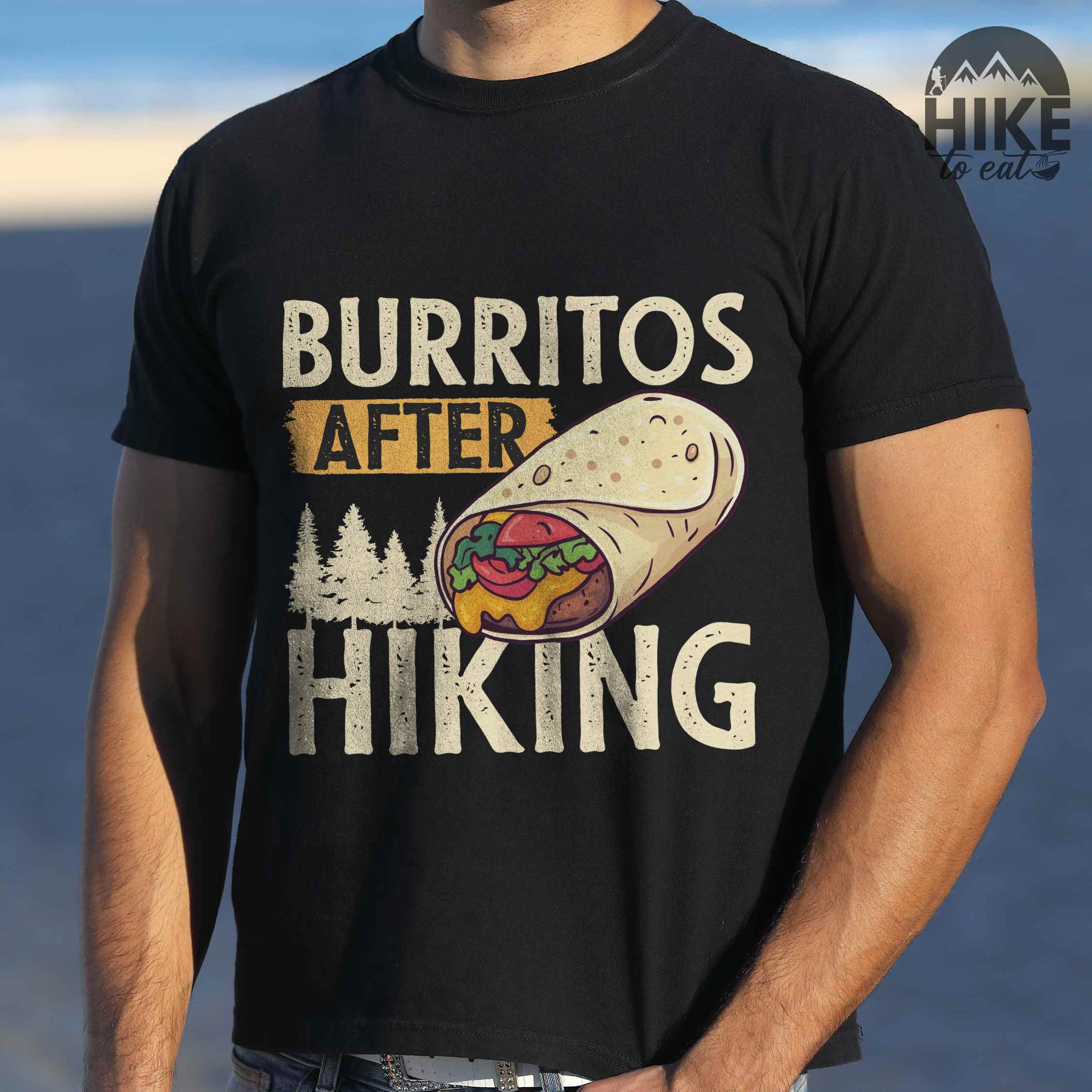 Man wearing black "burritos after hiking" colored vintage tee with bold typography, birds, trees, illustrated wrapped burrito, and backpacker for burrito enthusiasts.