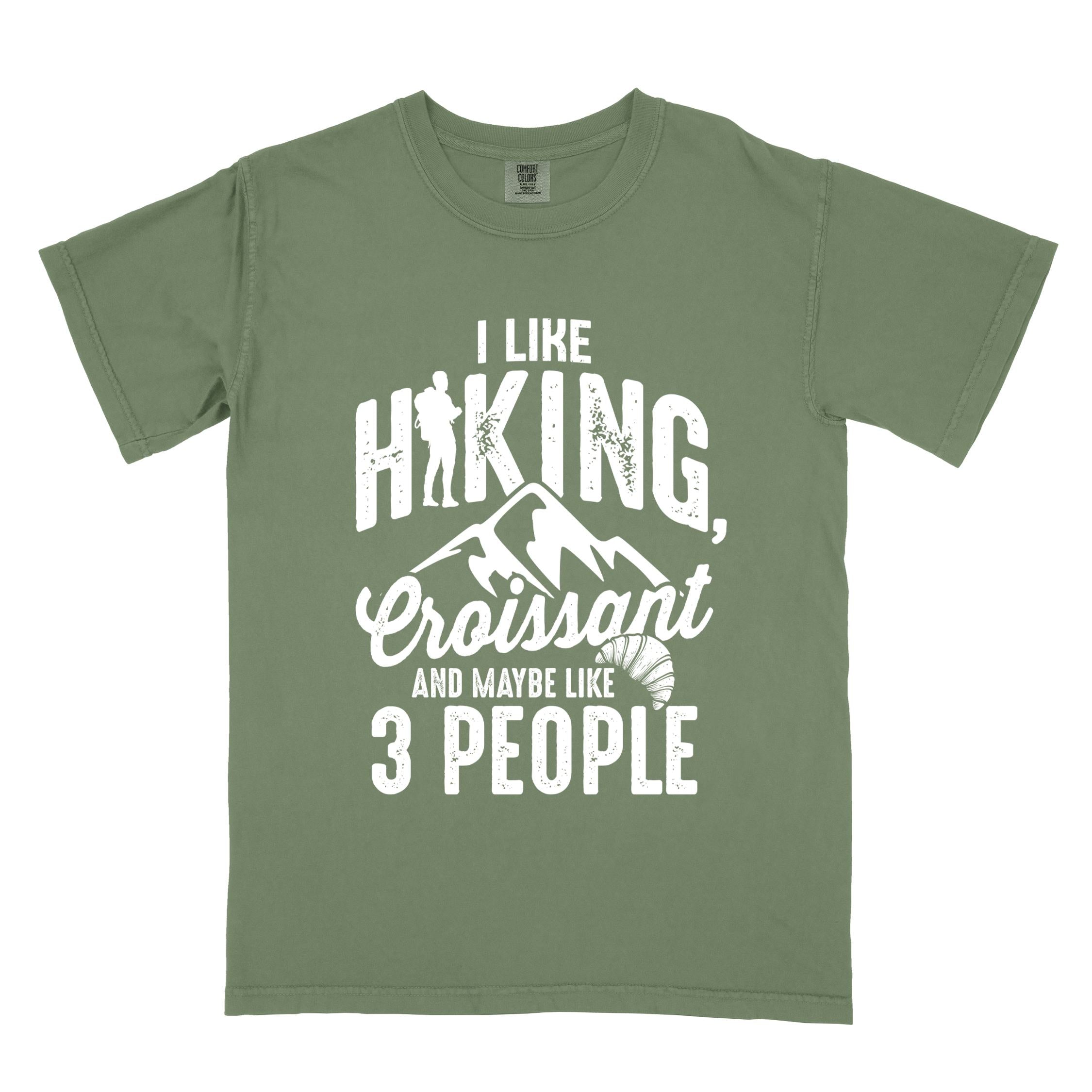 Moss "I Like hiking, croissant and maybe like 3 people" colored vintage tee with bold typography, birds, mountains, illustrated croissant, and backpacker for pastry enthusiasts.