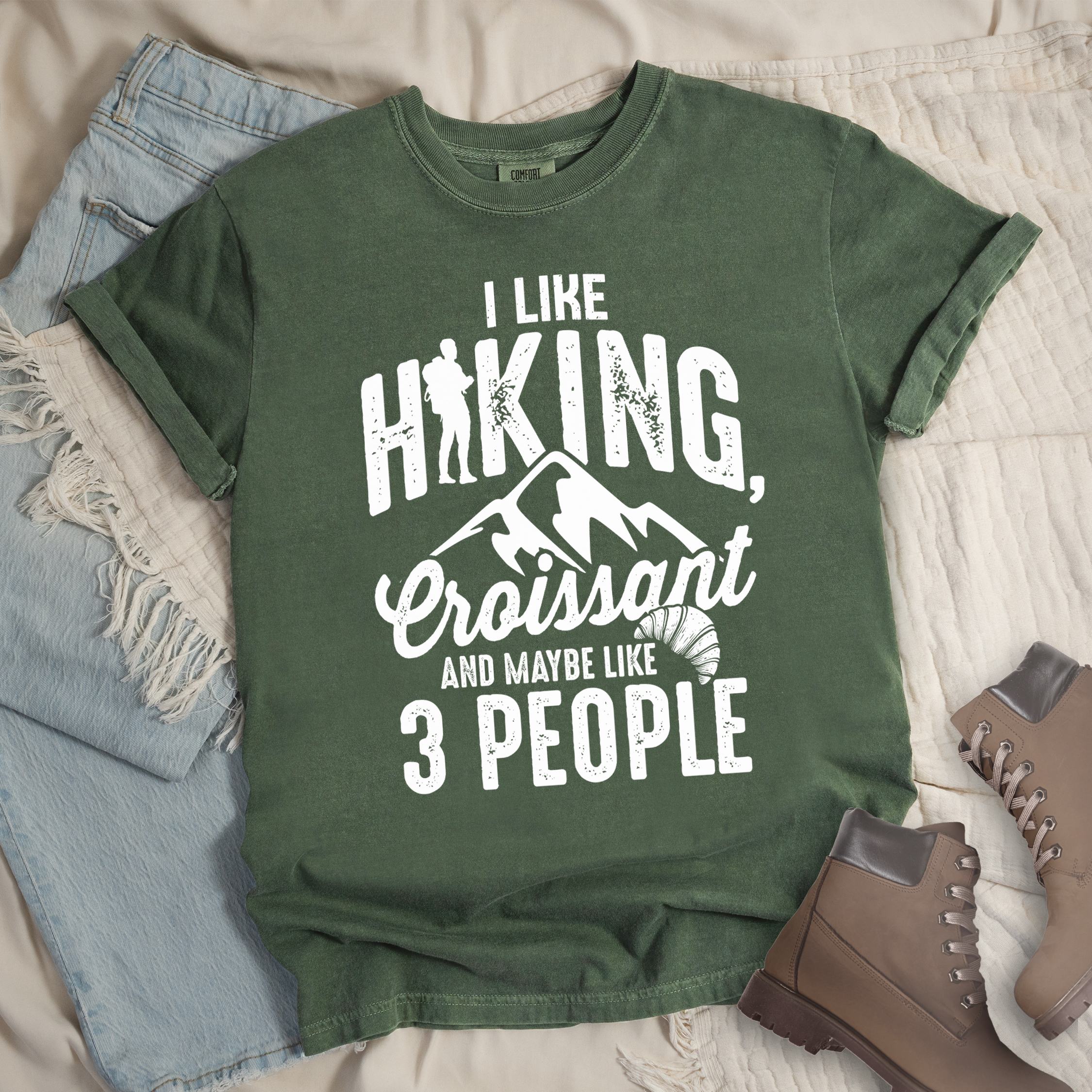 Dark green shirt with Hiking Design featuring the phrase “I Like Hiking, Croissant, and Maybe Like 3 People” and an illustration of a croissant below mountain outlines.