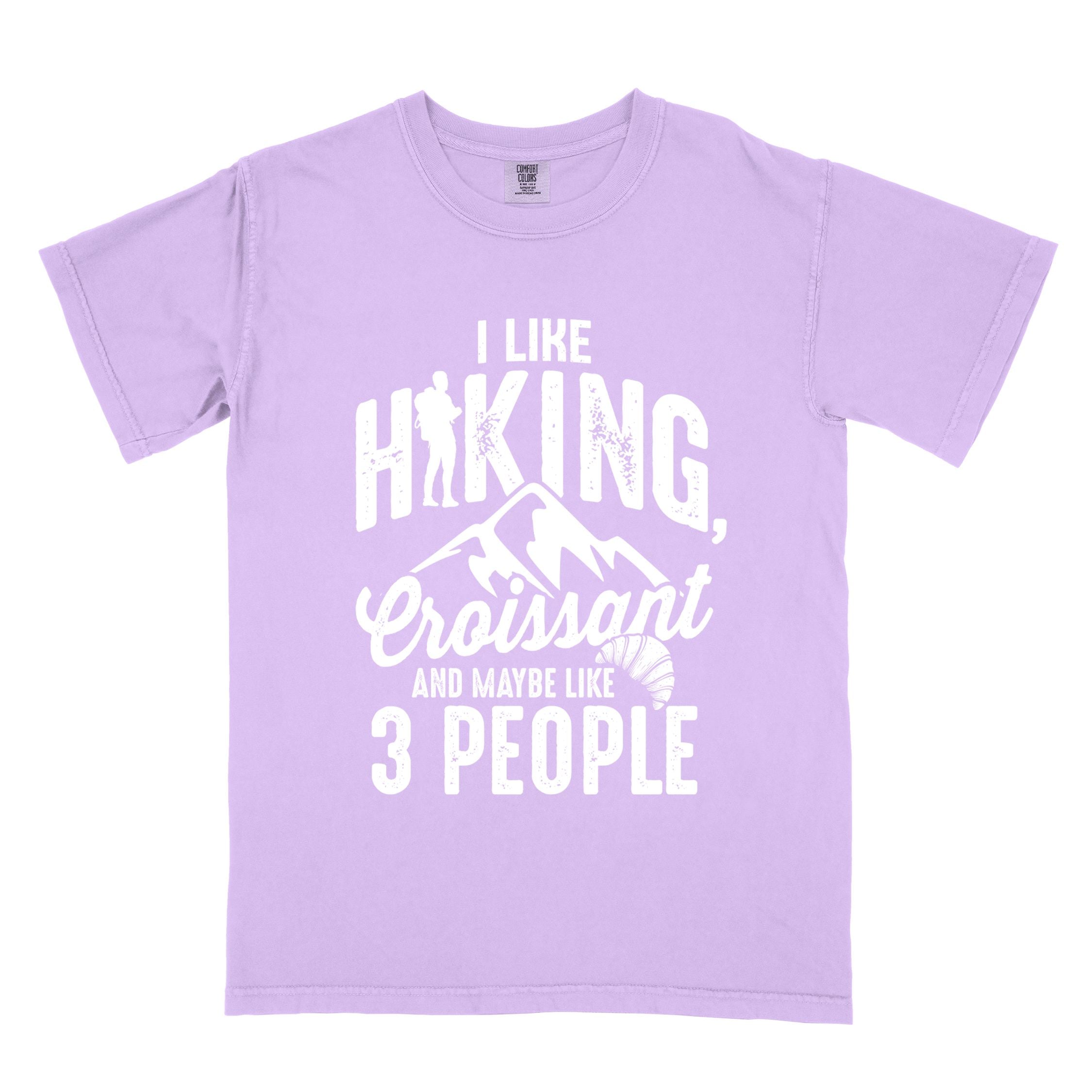 Orchid "I Like hiking, croissant and maybe like 3 people" colored vintage tee with bold typography, birds, mountains, illustrated croissant, and backpacker for pastry enthusiasts.